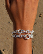 Silver chain bracelet on a wrist with a sandy background