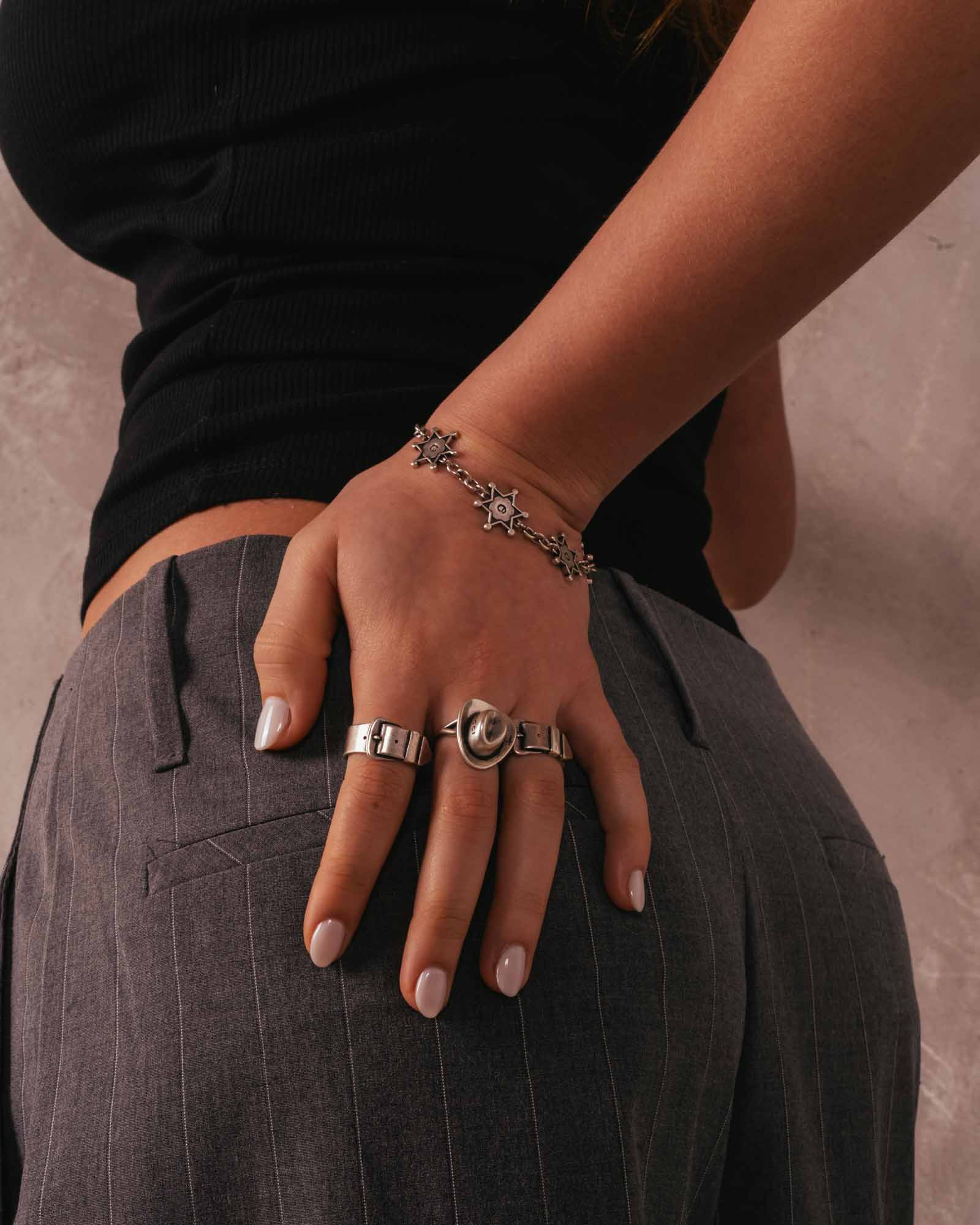 Person wearing multiple rings and a bracelet on a neutral background  - Rodeo Hat Ring 