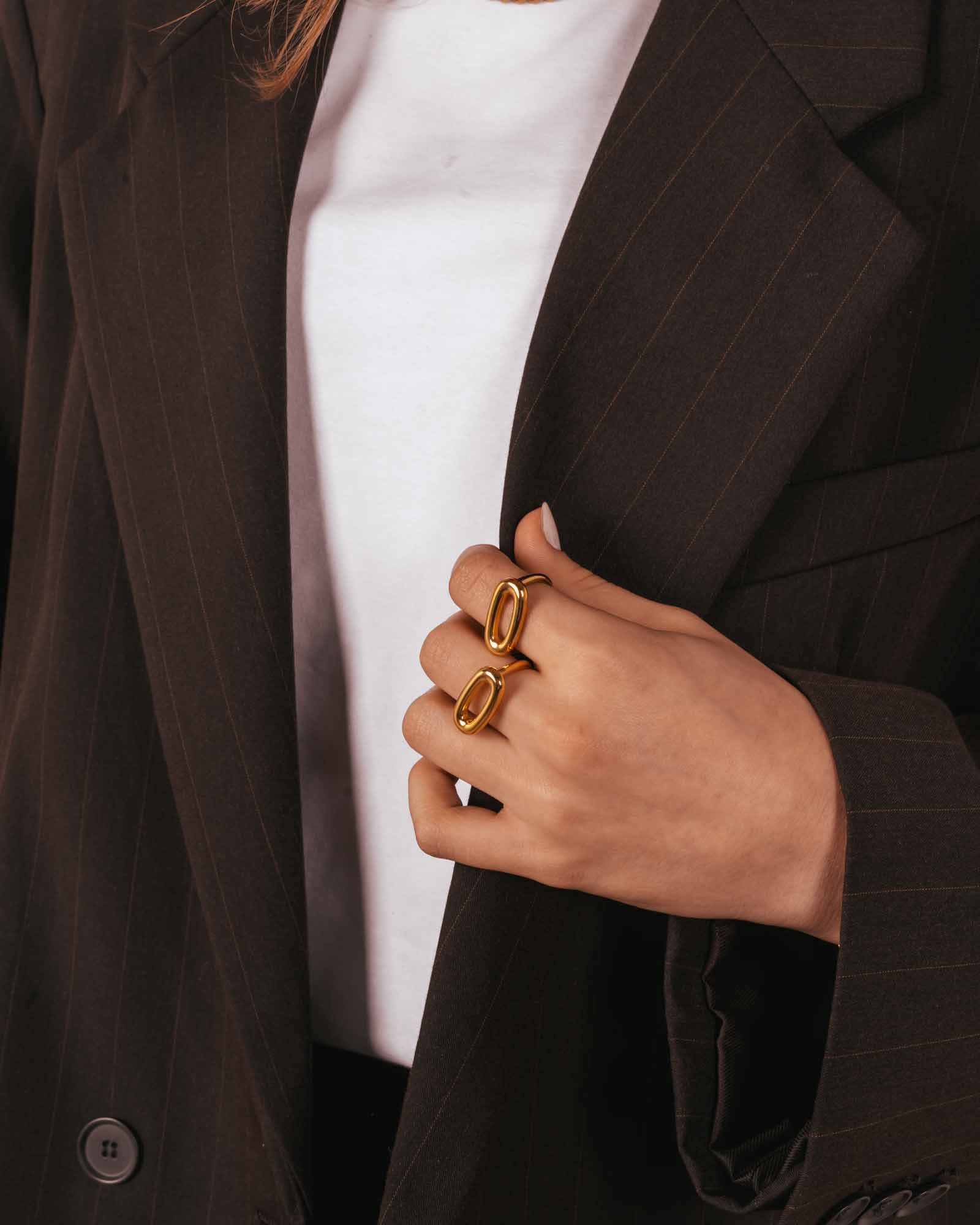 Person wearing a dark pinstripe suit with gold rings on a white background