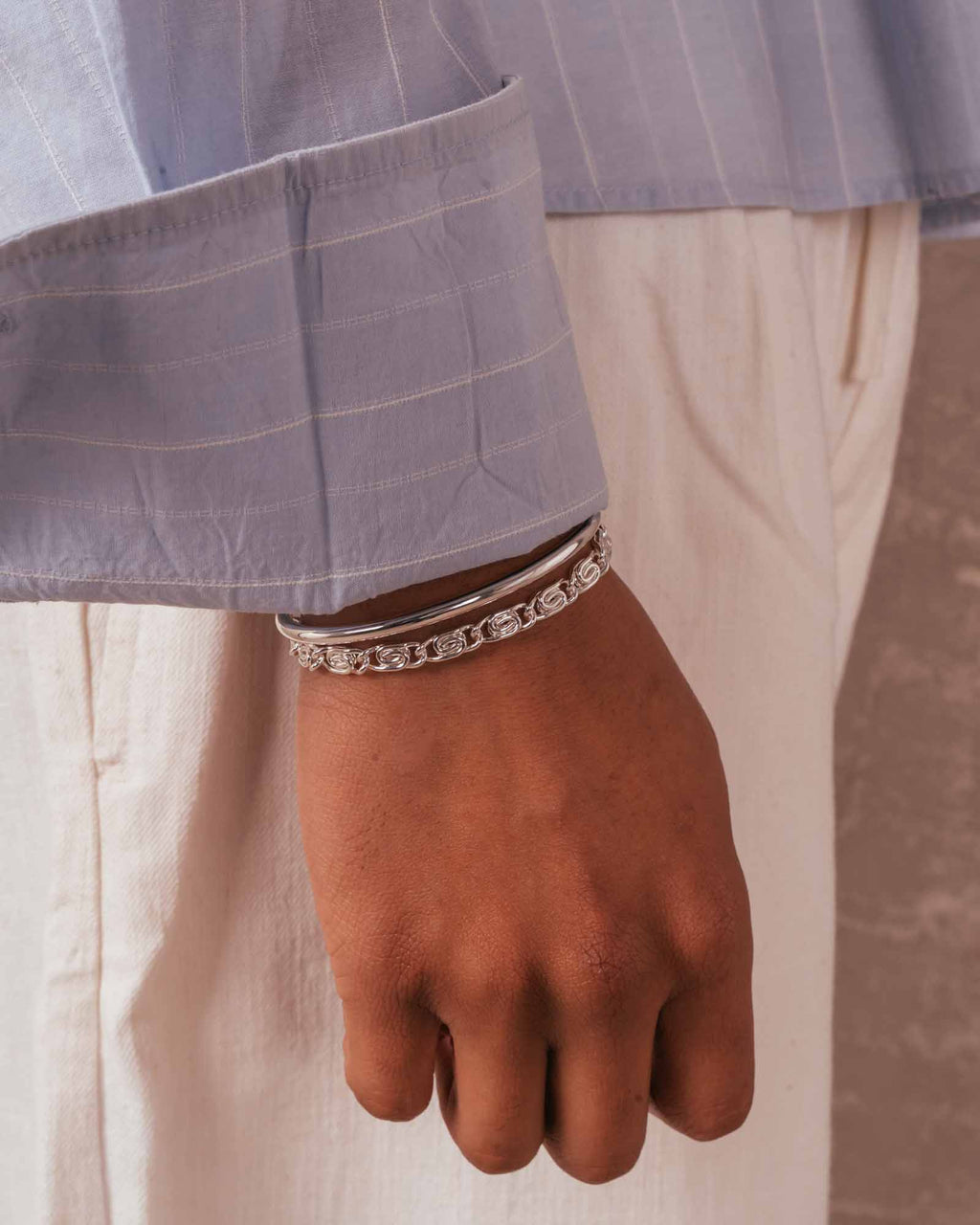 Hand wearing multiple bracelets with a blurred background