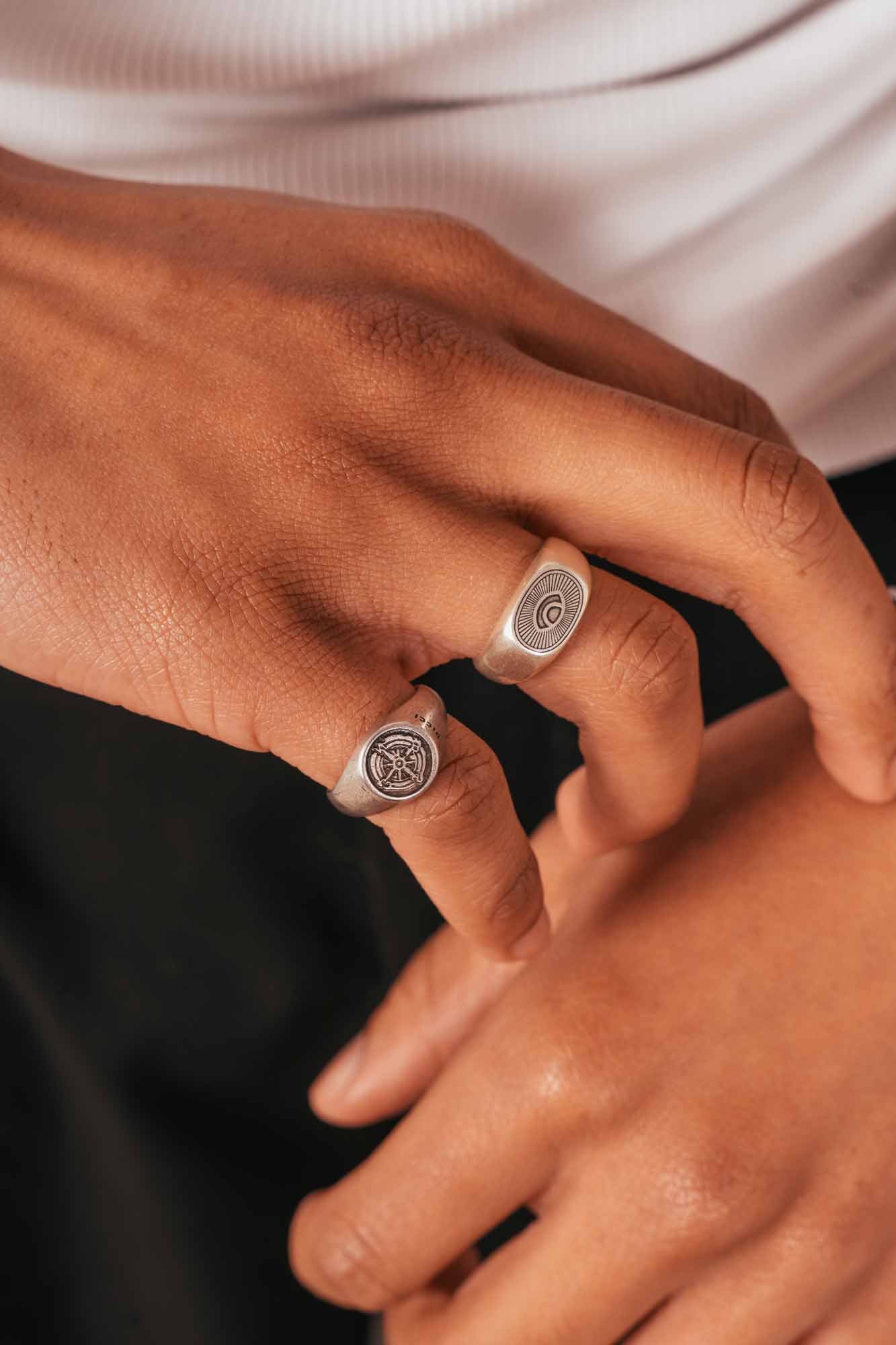 Close-up of a hand wearing two silver rings on a neutral background