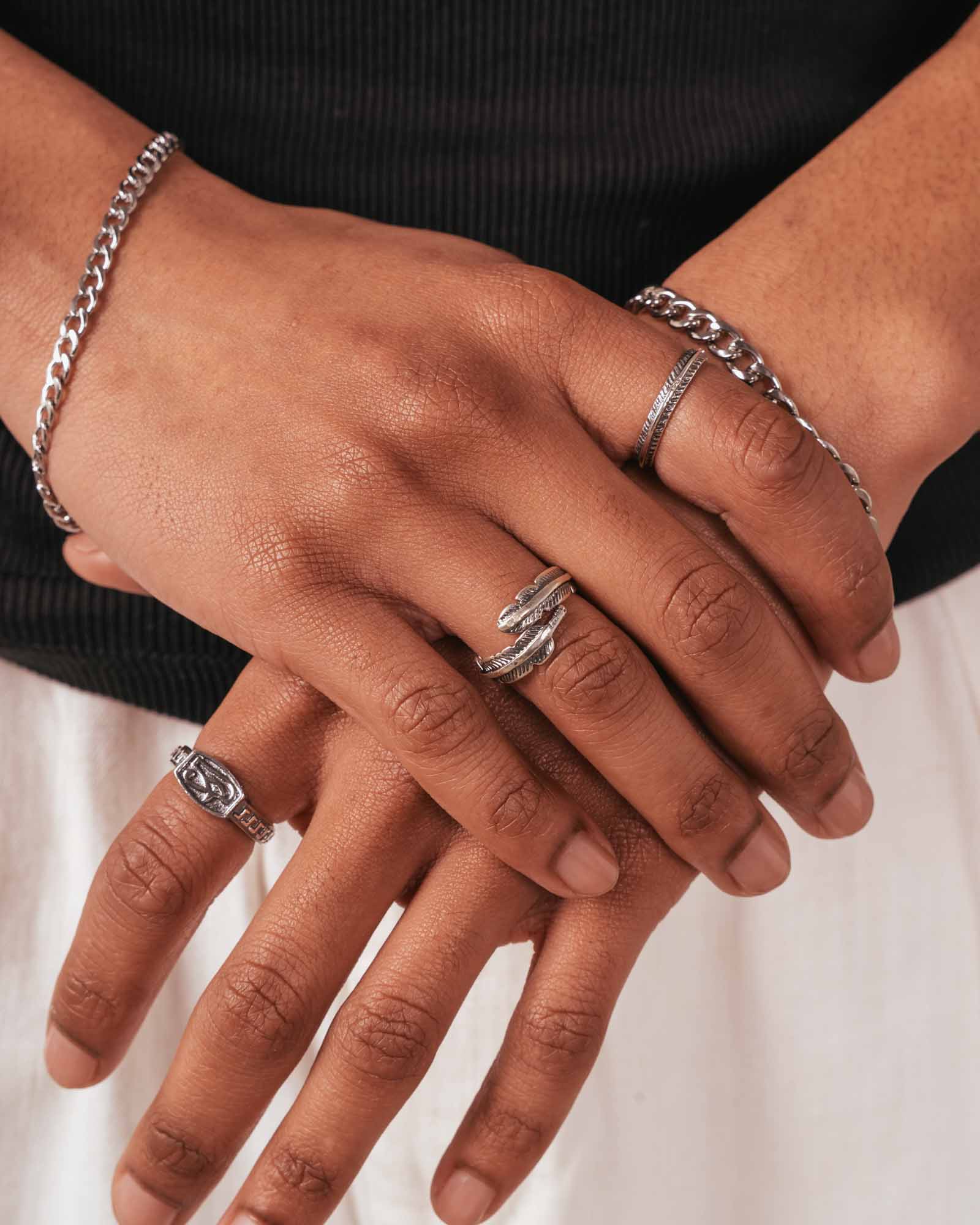Close-up of hands with silver rings and bracelets on a neutral background
