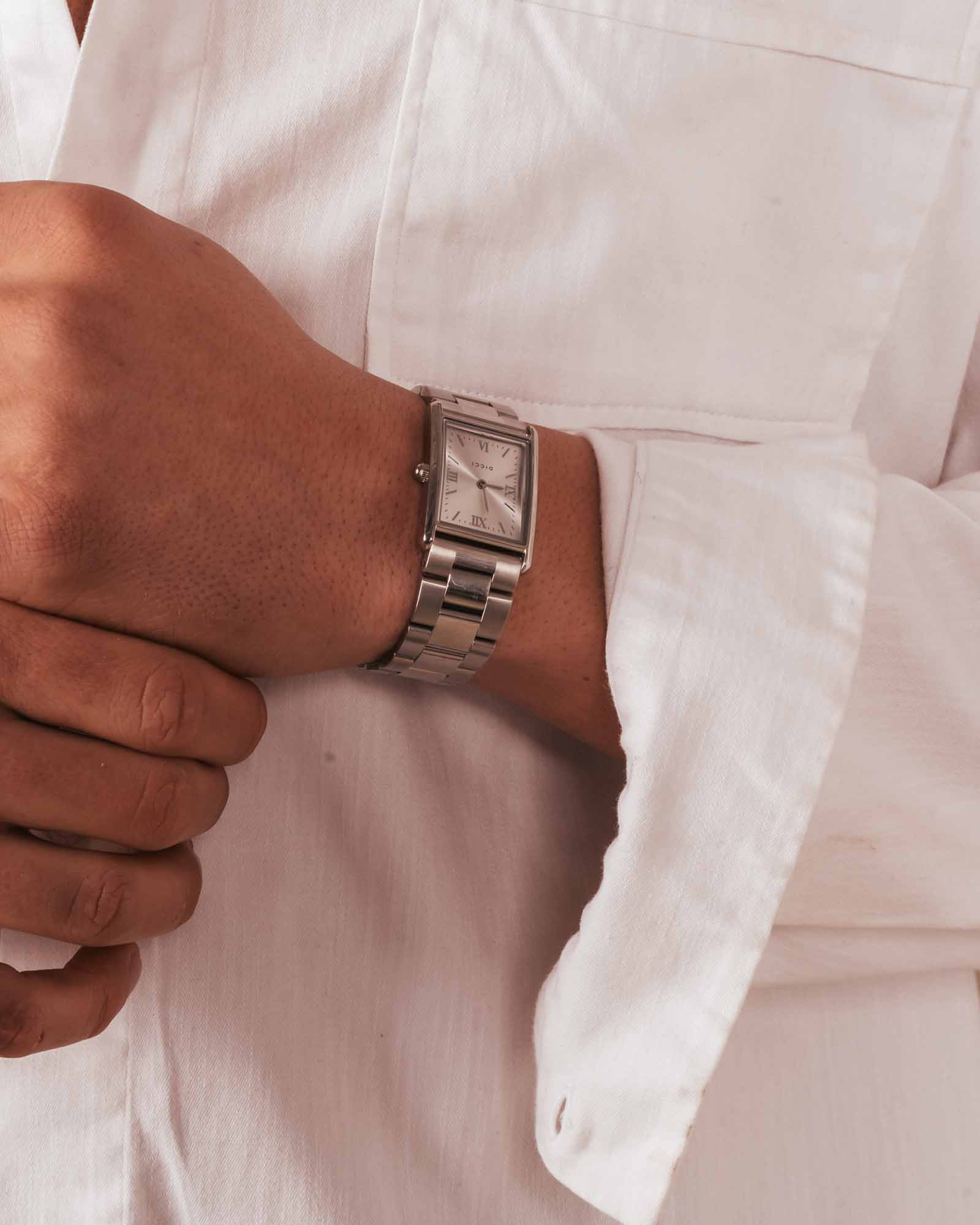 Hand wearing a silver watch on a white background
