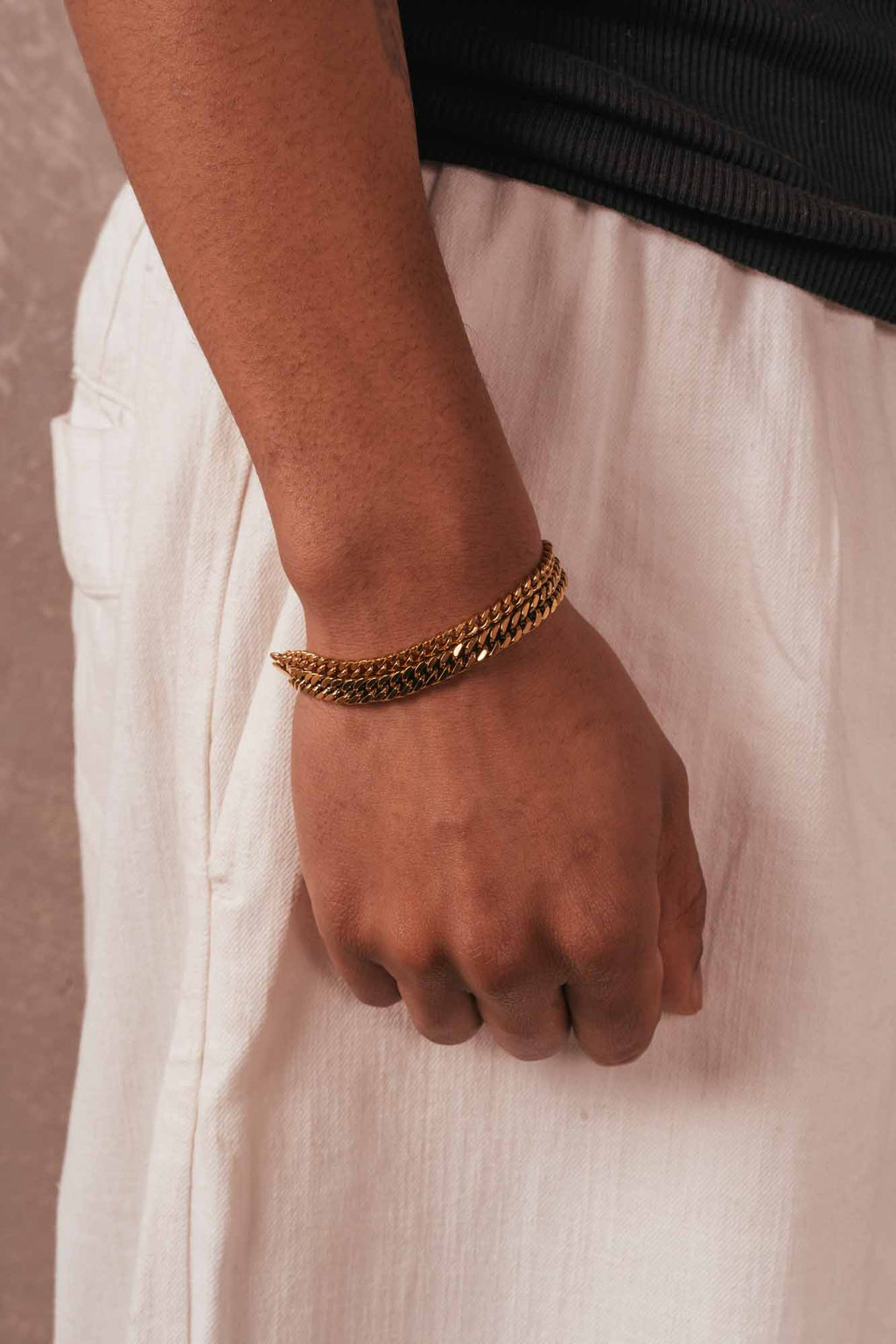Hand wearing a gold bracelet on a white background