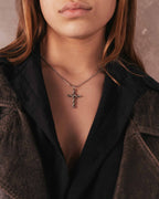 Person wearing a twisted cross necklace in stainless steel