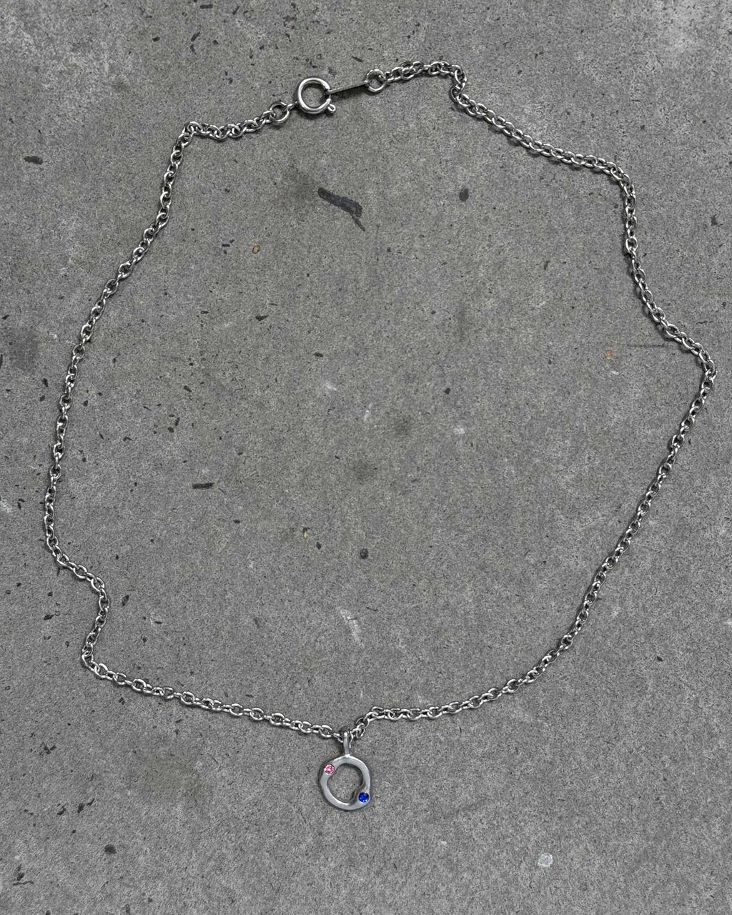 Silver chain bracelet with a small charm on a concrete surface