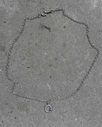 Silver chain bracelet with a small charm on a concrete surface