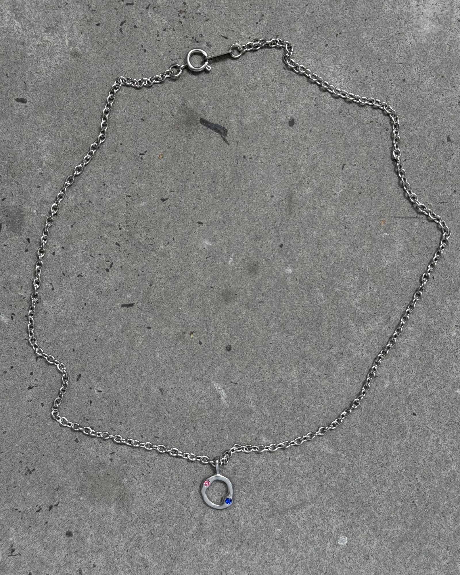 Silver chain bracelet with a small charm on a concrete surface