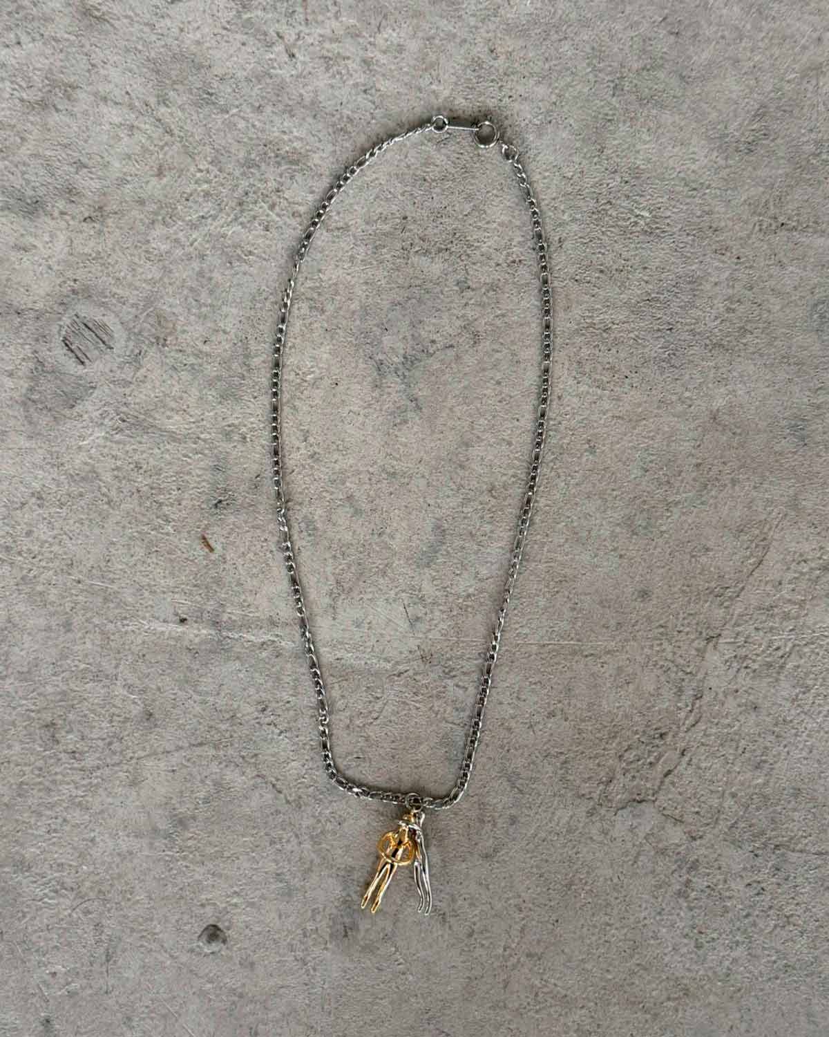 Couple Hug Necklace featuring intertwining figures in silver and gold on a minimalist chain background.