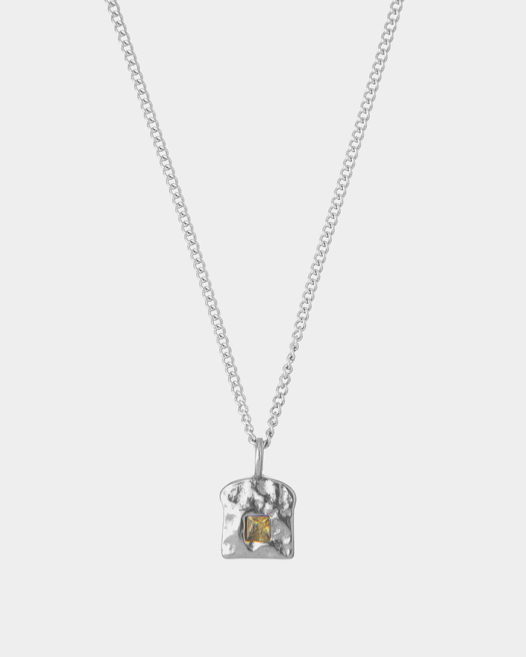 Silver necklace with a textured pendant and a emerald on a white background