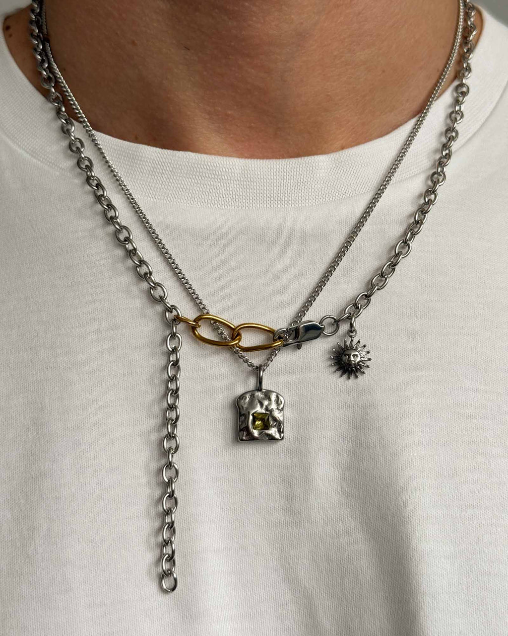 Necklace with various pendants on a white shirt