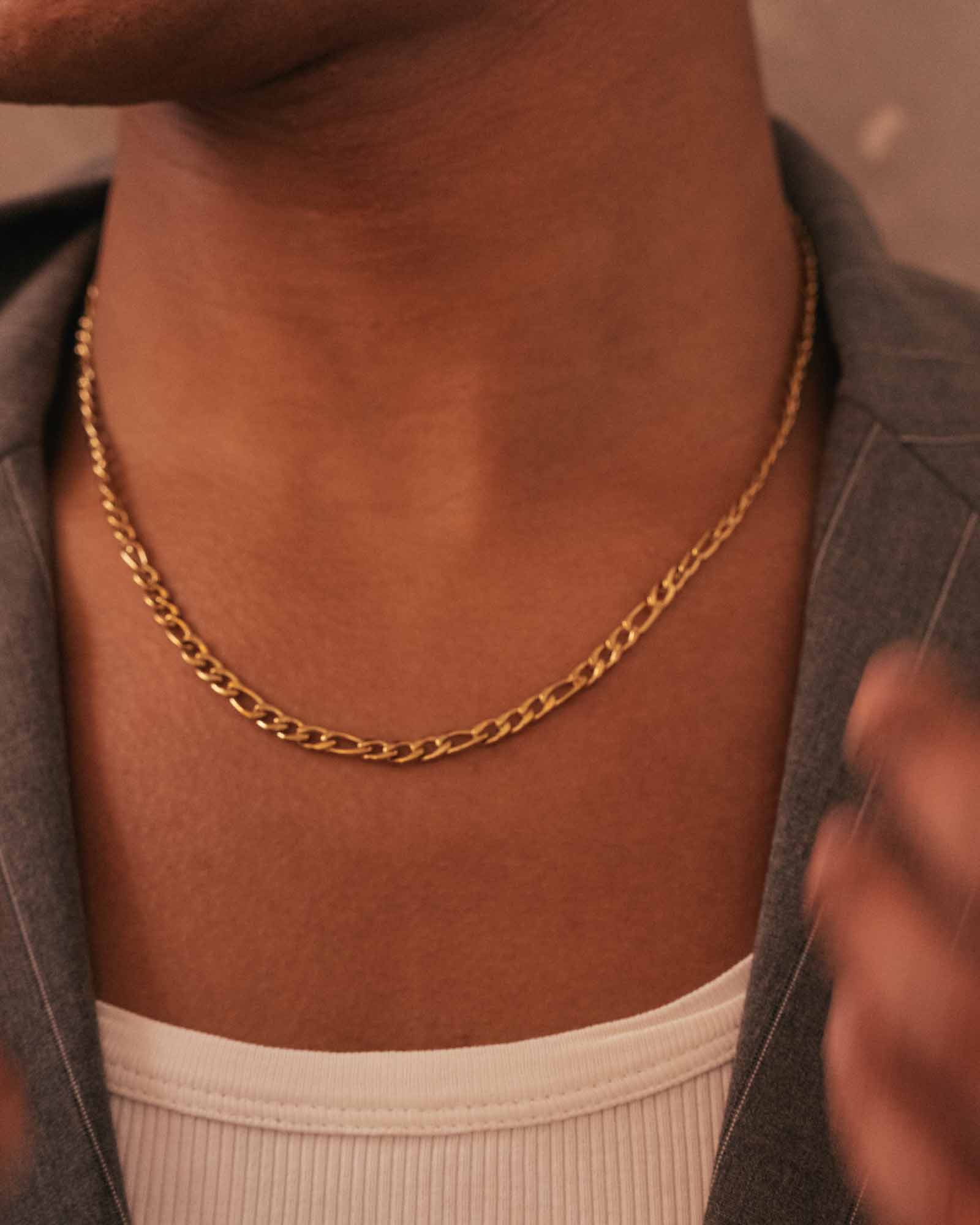 Golden chain necklace on a person's neck with a blurred background