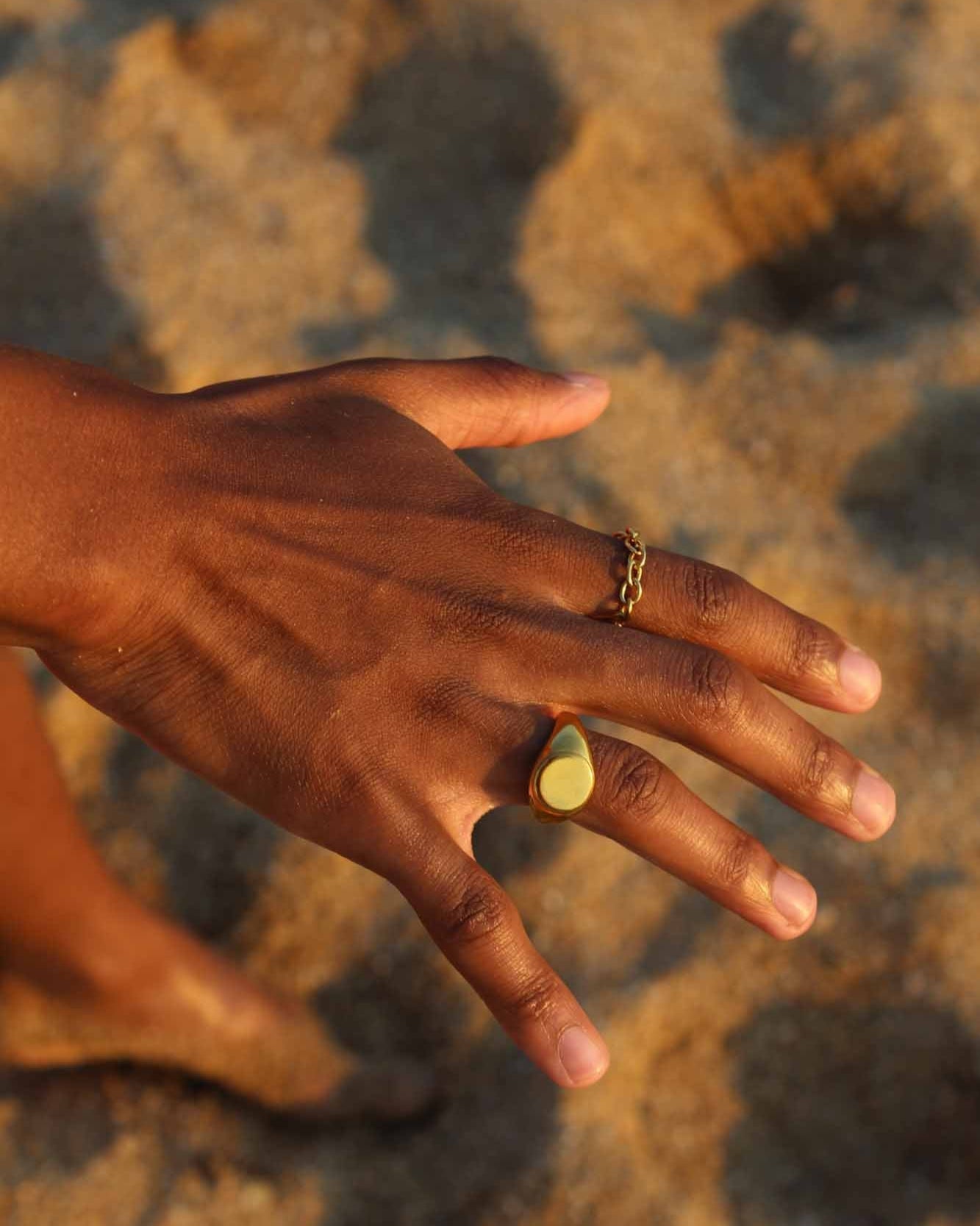 Golden cable ring worn by person on a neutral background