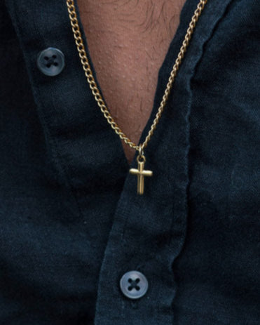 Man wearing the golden Caprera Golden Necklace with cross pendant and black shirt