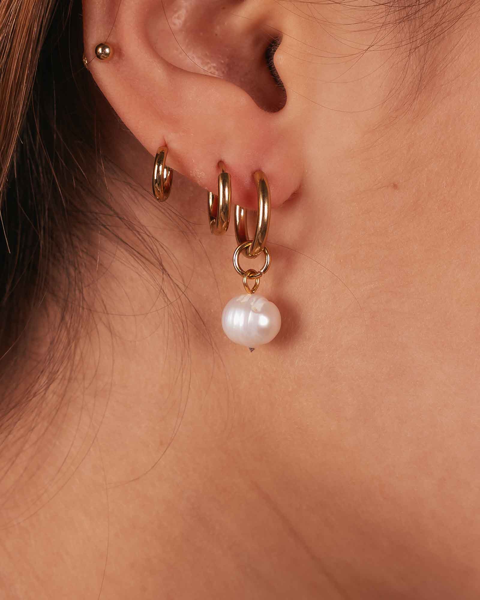Golden pearl drop earring detail