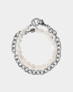 Bracciale con perle bianche e catena d'argento su sfondo grigio chiaro