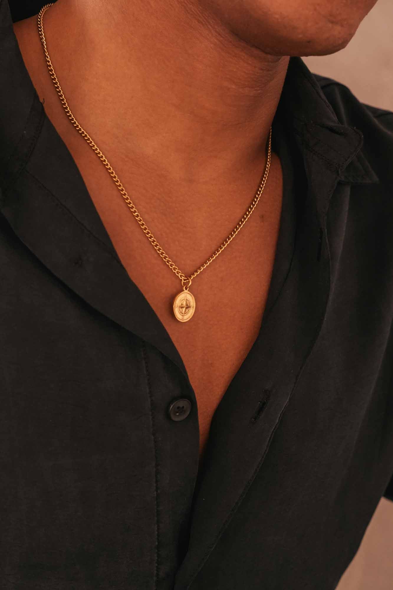 Person wearing a golden wind rose pendant necklace