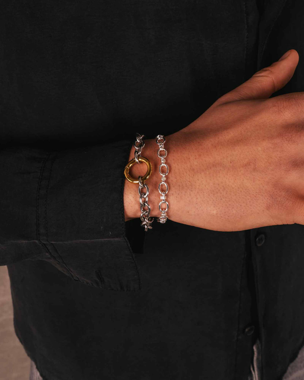 Person wearing a silver chain bracelet on a black background