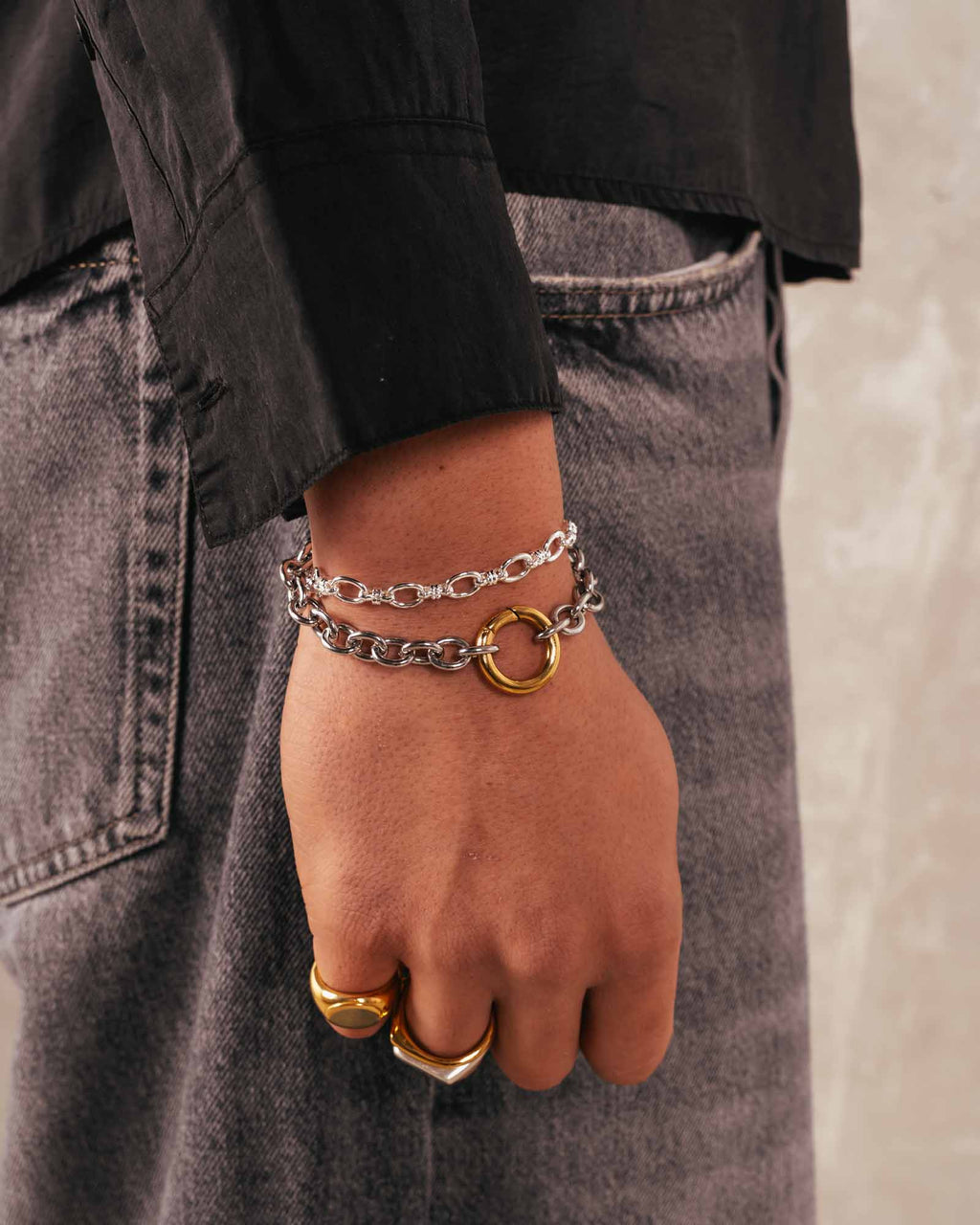 Person wearing a silver strand bracelet on a black background