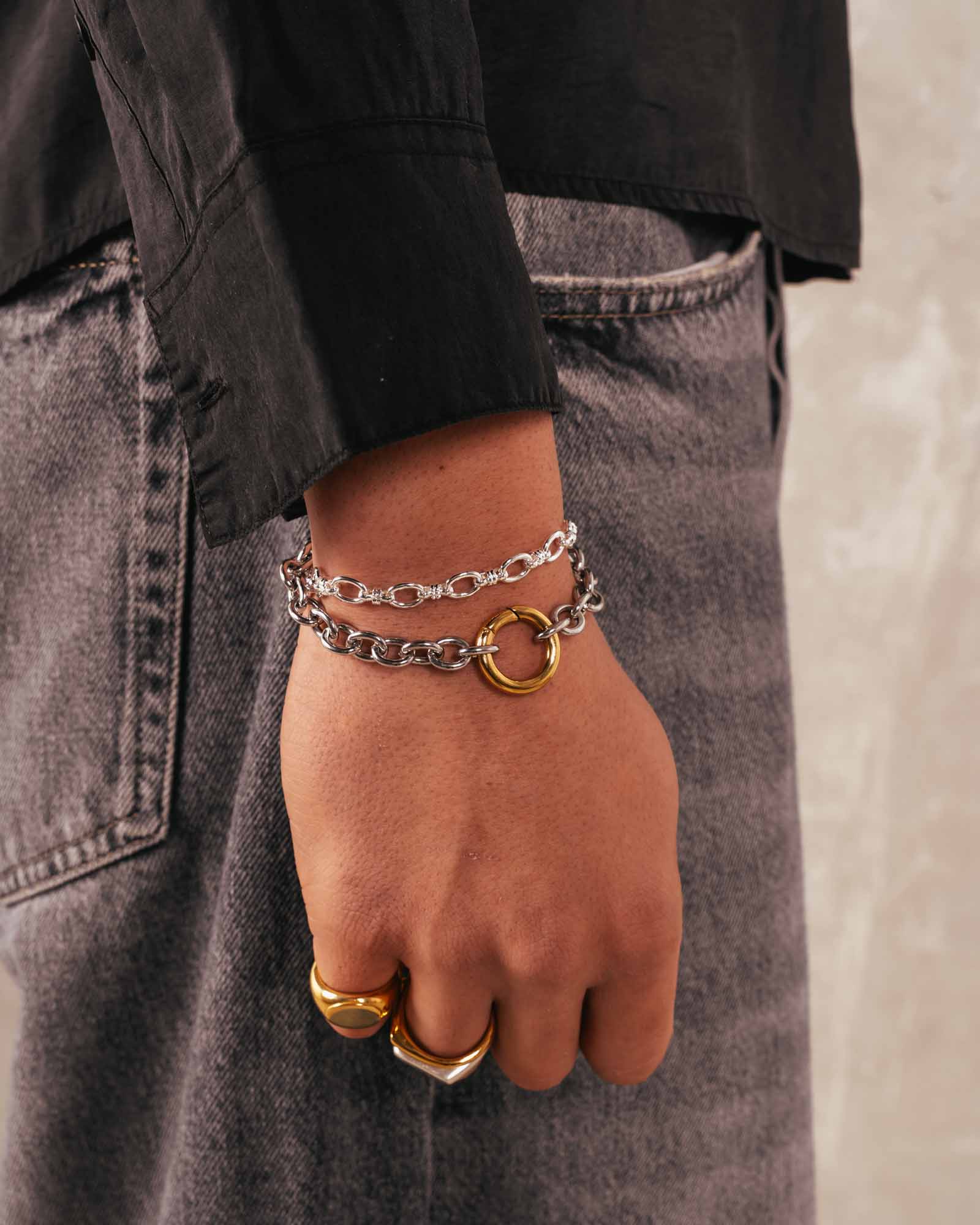 Person wearing a silver strand bracelet on a black background