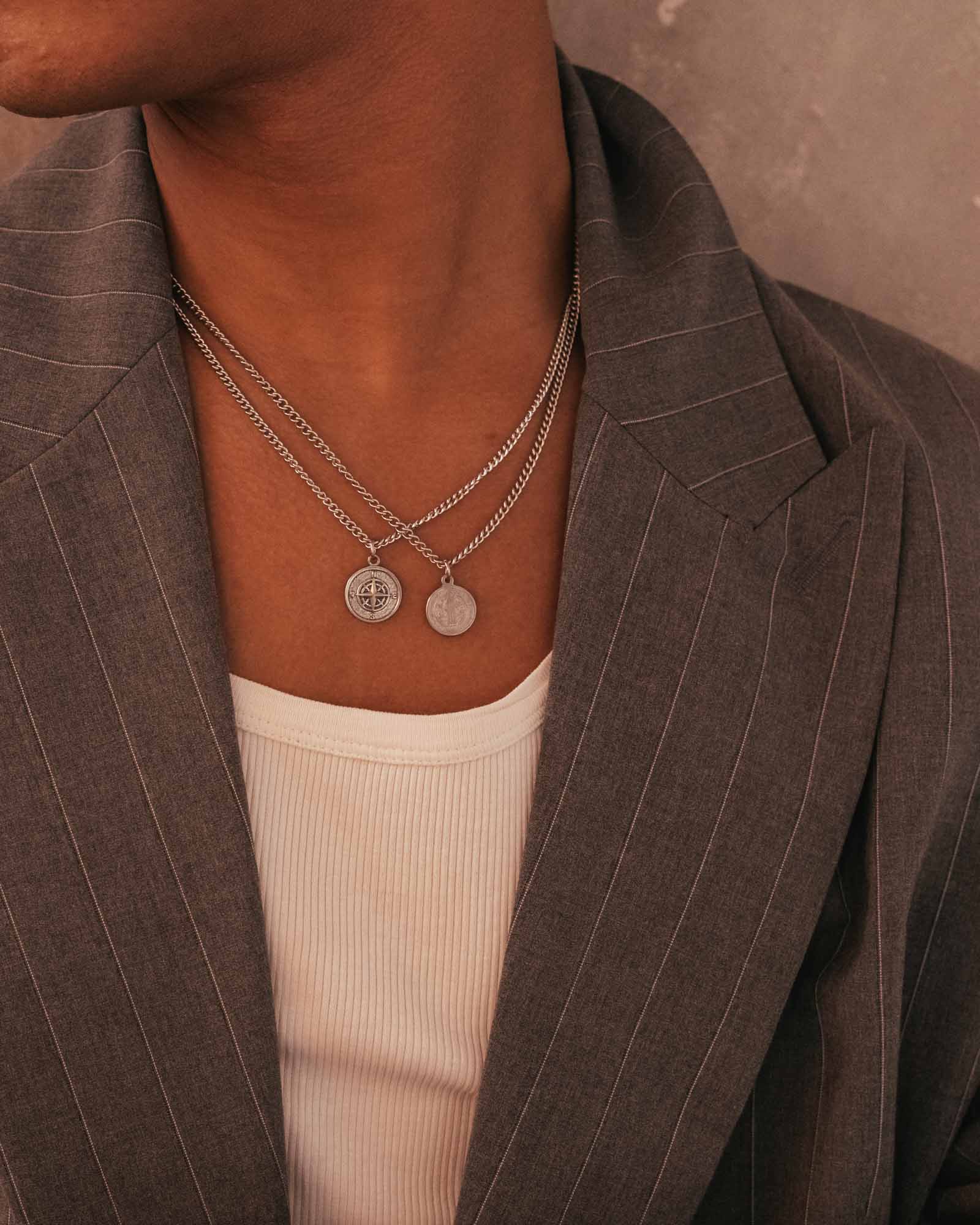 Person wearing a silver wind rose pendant necklace on a neutral background