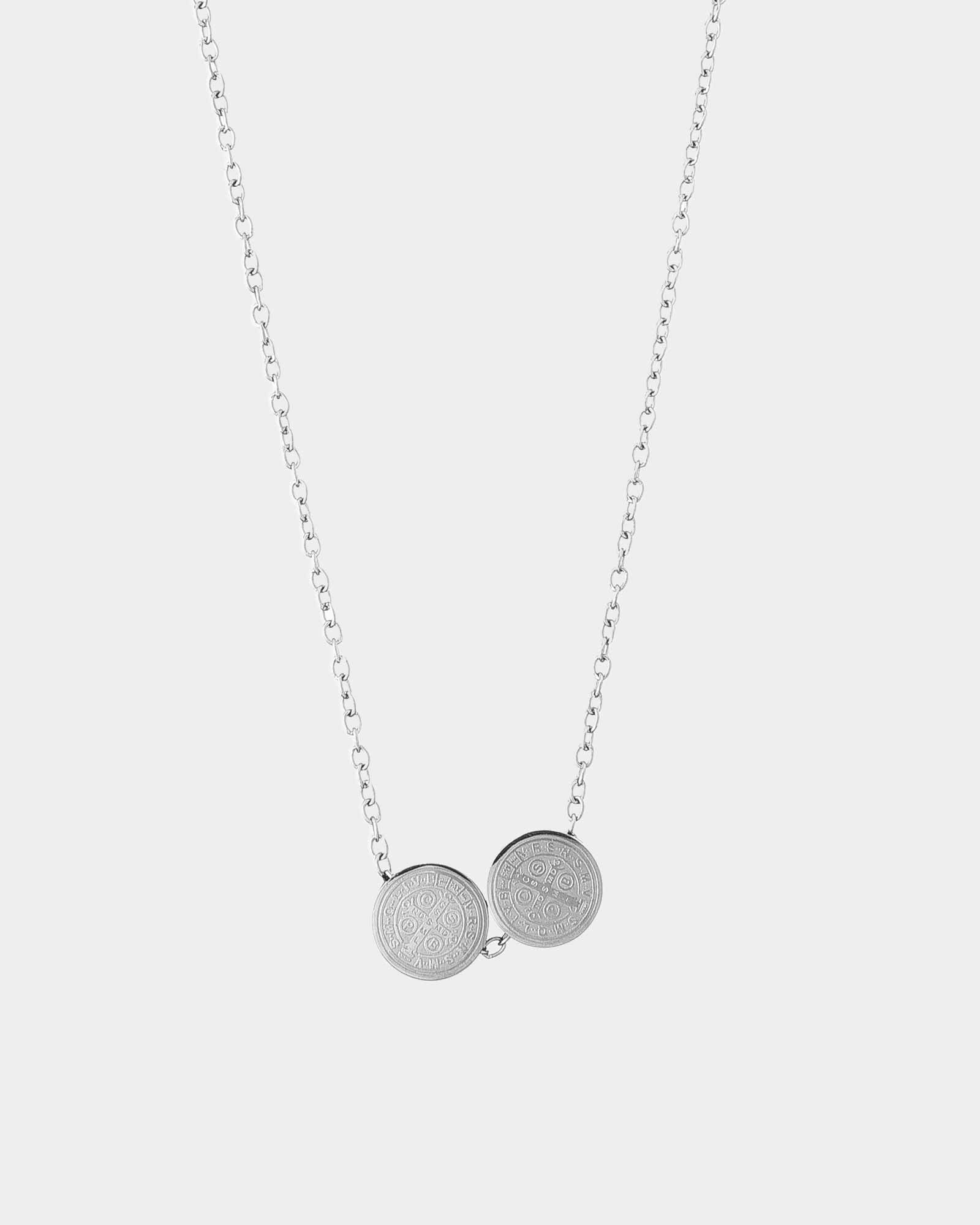 Silver necklace with two round pendants on a light gray background