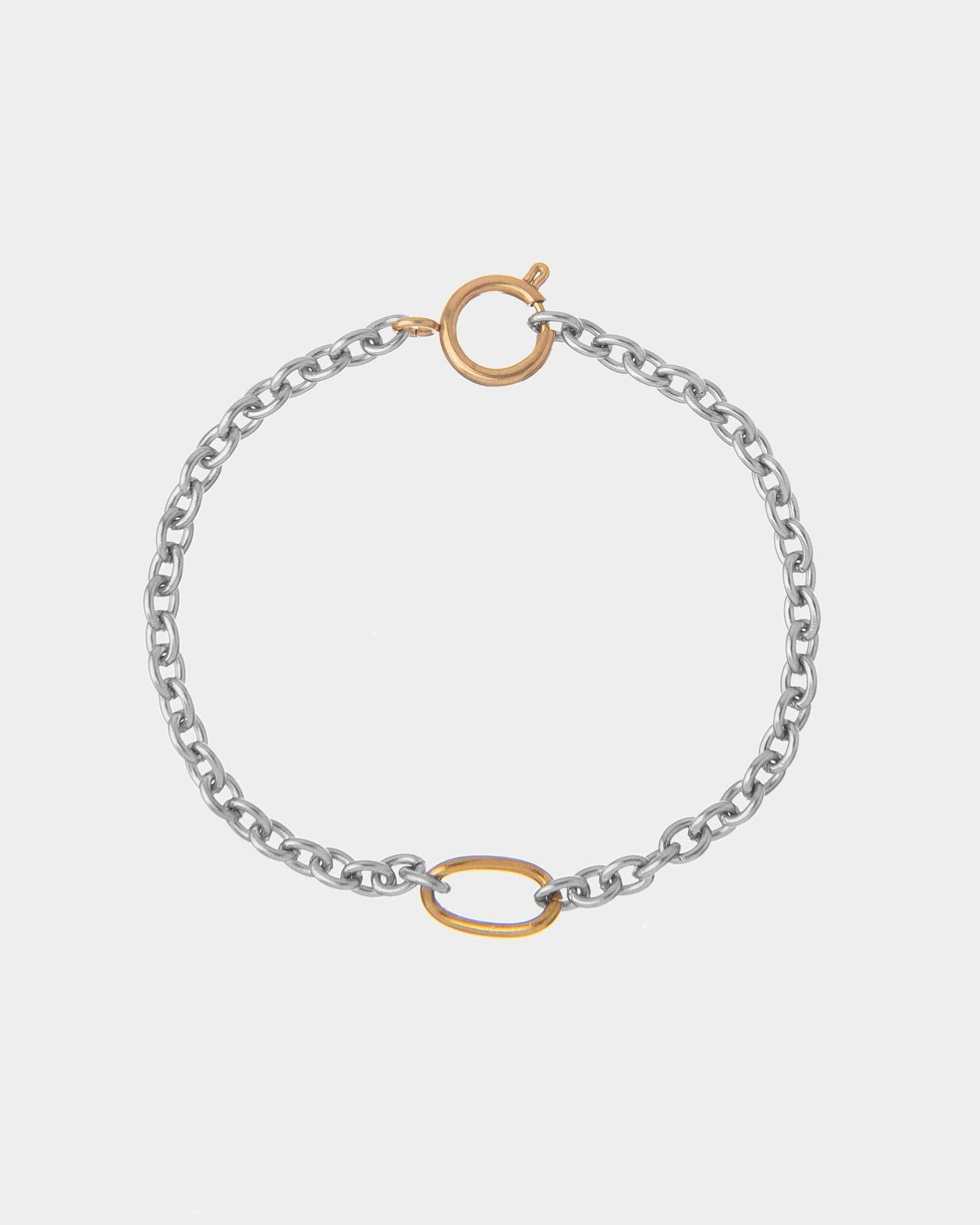 Silver chain bracelet with gold clasp on a light gray background