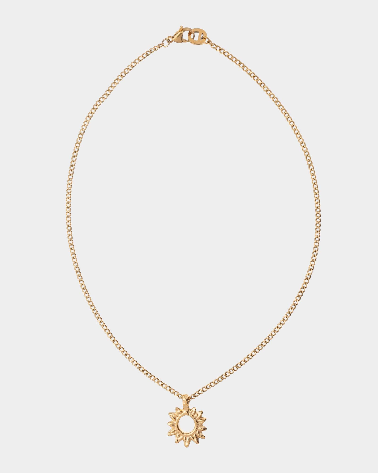 Gold necklace with a sun pendant on a light gray background