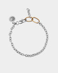 Silver chain bracelet with gold accents and a sun charm on a light gray background