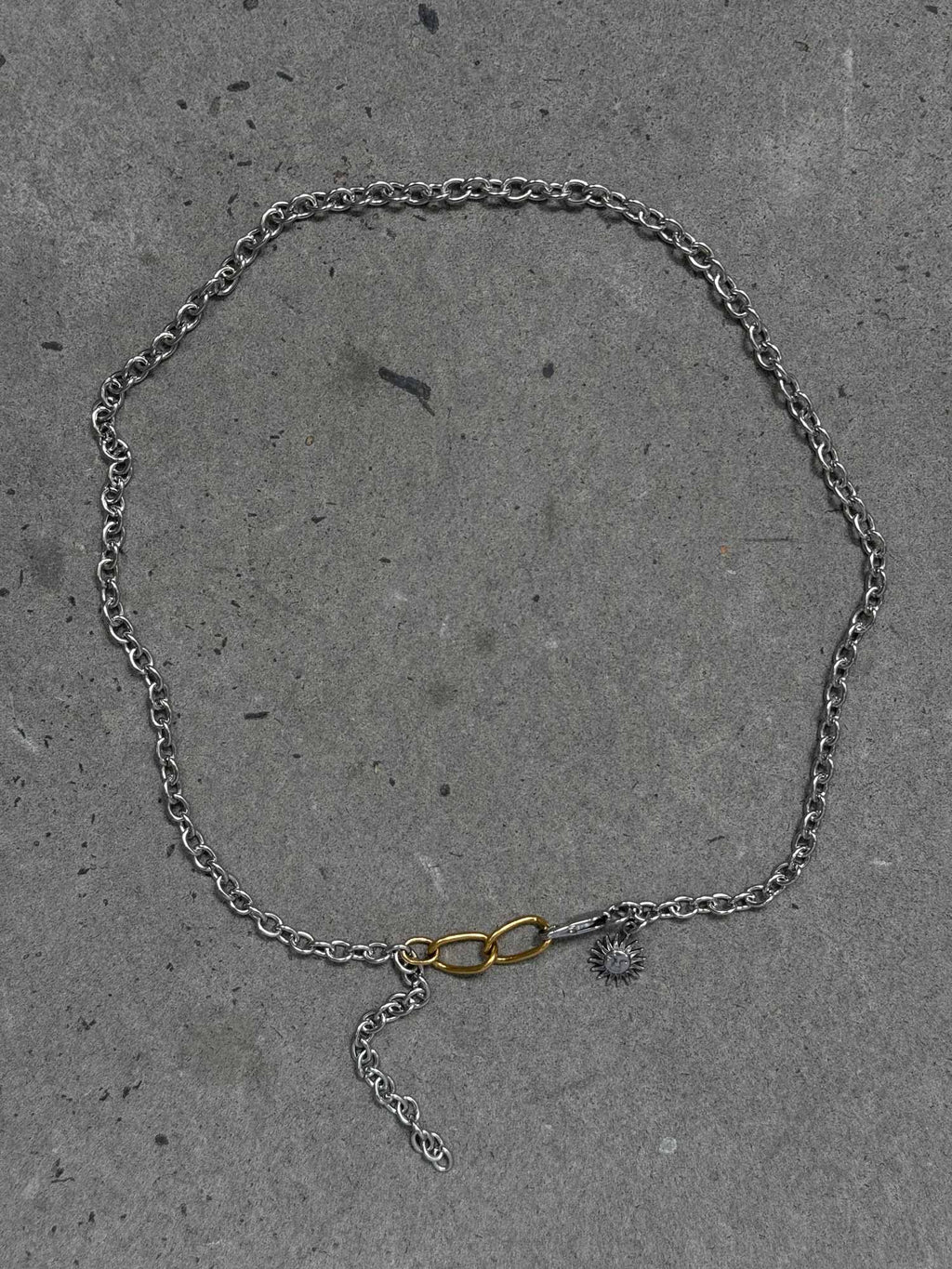 Silver chain necklace with a unique clasp on a gray concrete surface