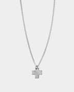Collar de cruz de plata sobre un fondo gris claro