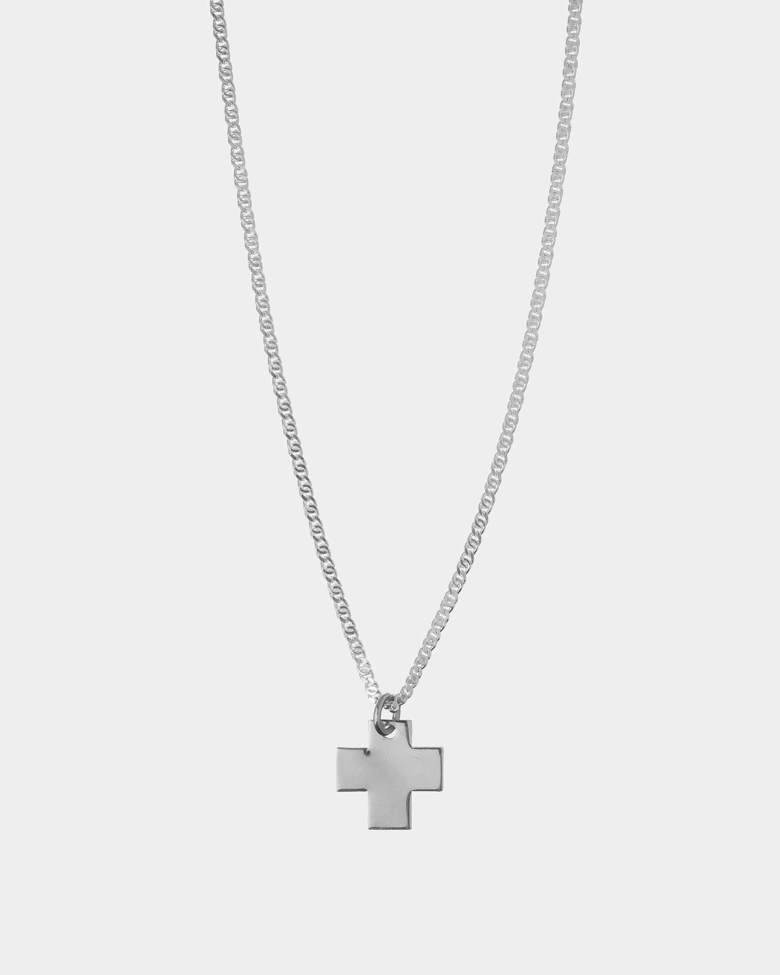 Silver cross necklace on a light gray background