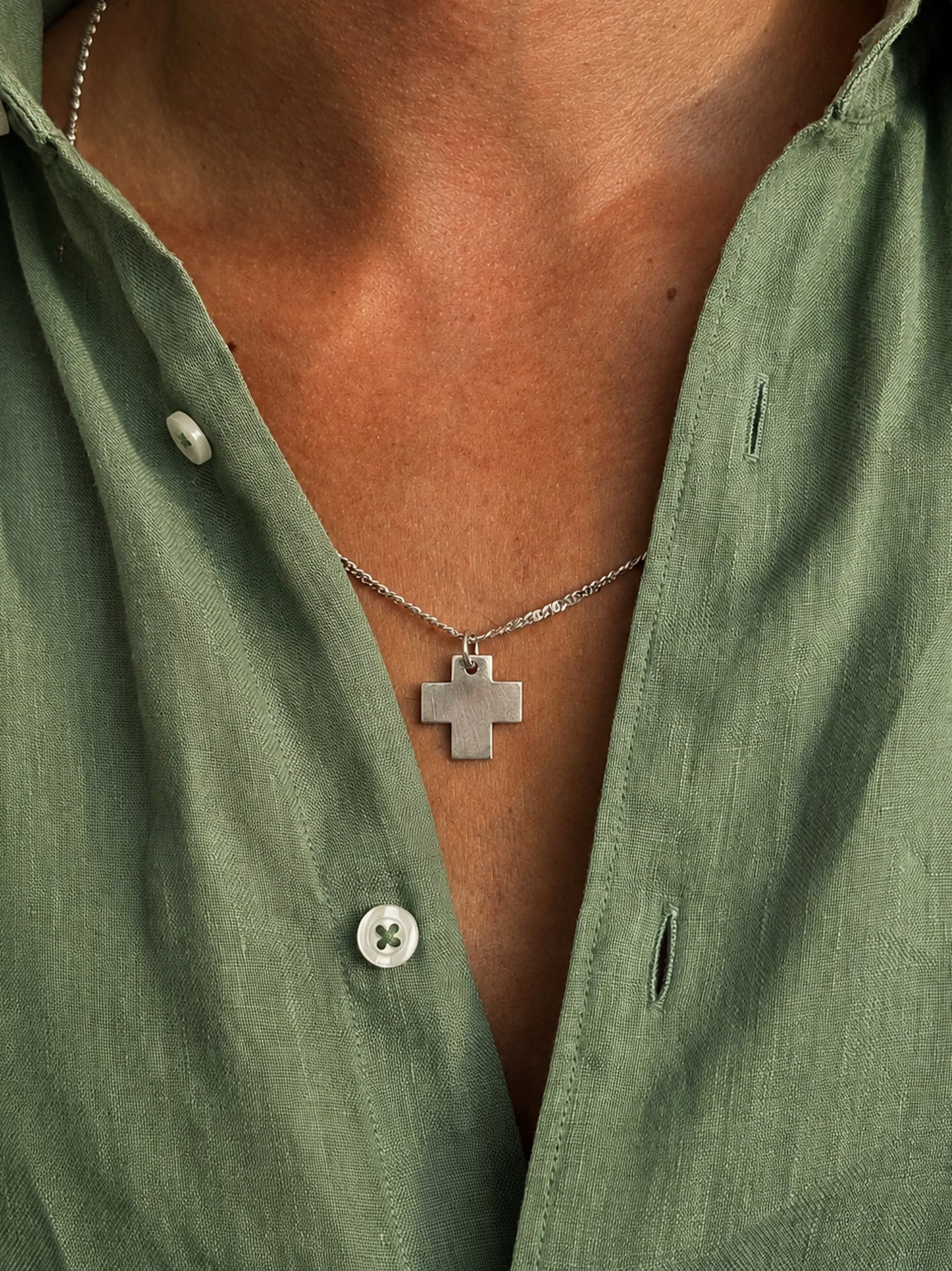 man wearing silver cross pendante