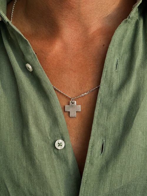 man wearing silver cross pendante