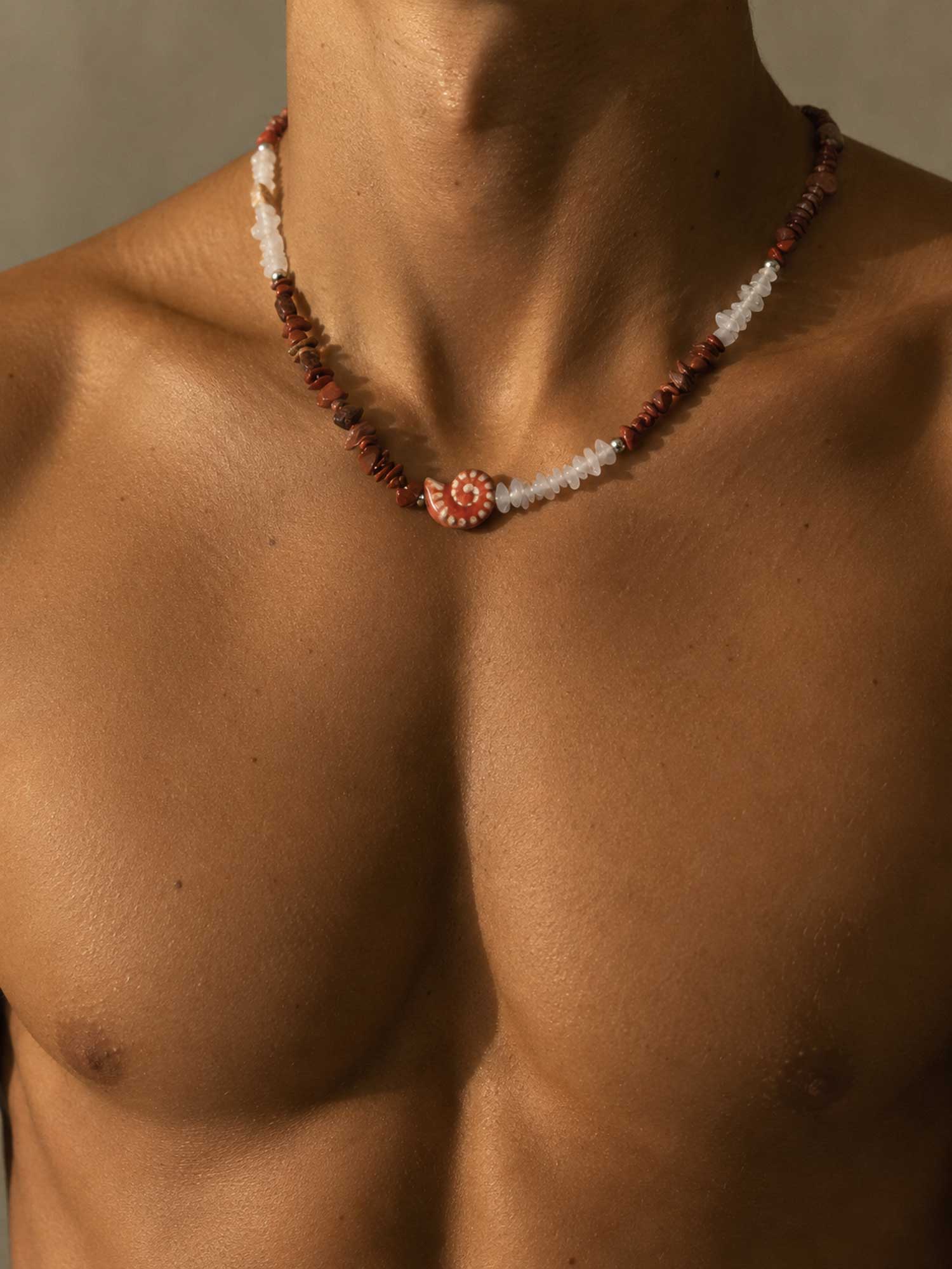 Necklace with a floral pendant on a person's chest against a neutral background
