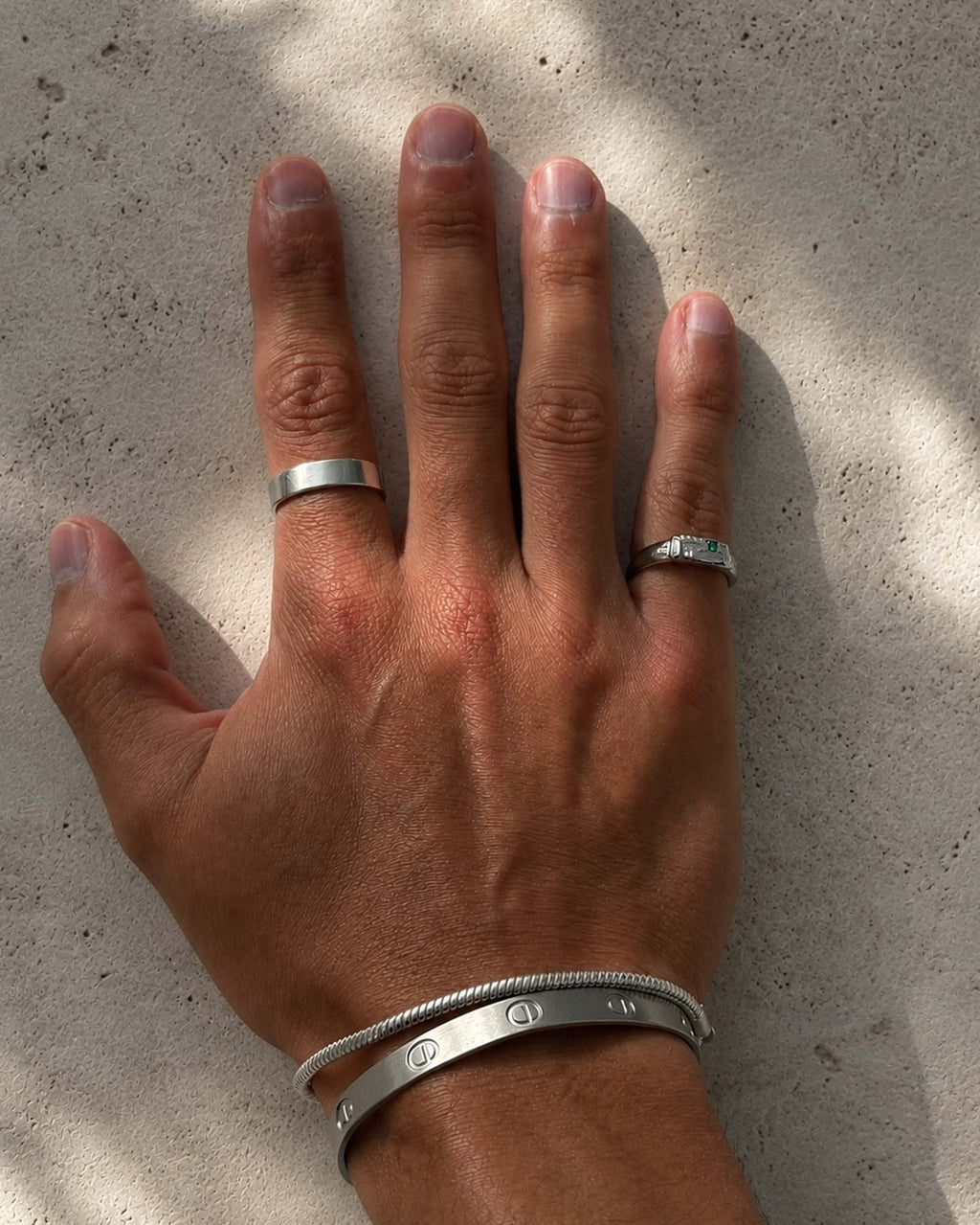 man wering silver rings and bracelets