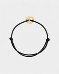 Black cord bracelet with a golden clasp on a light gray background