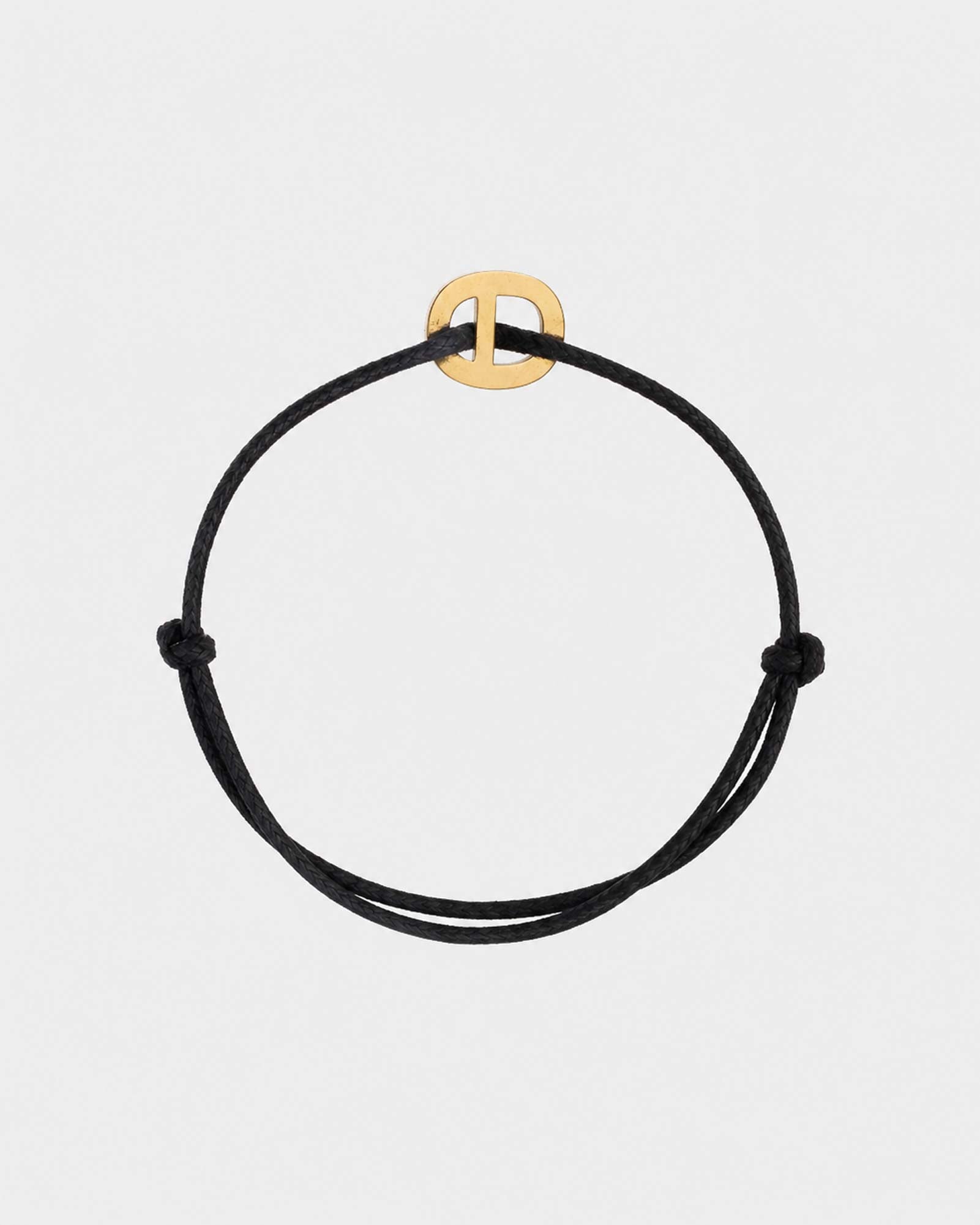Black cord bracelet with a gold clasp on a light gray background