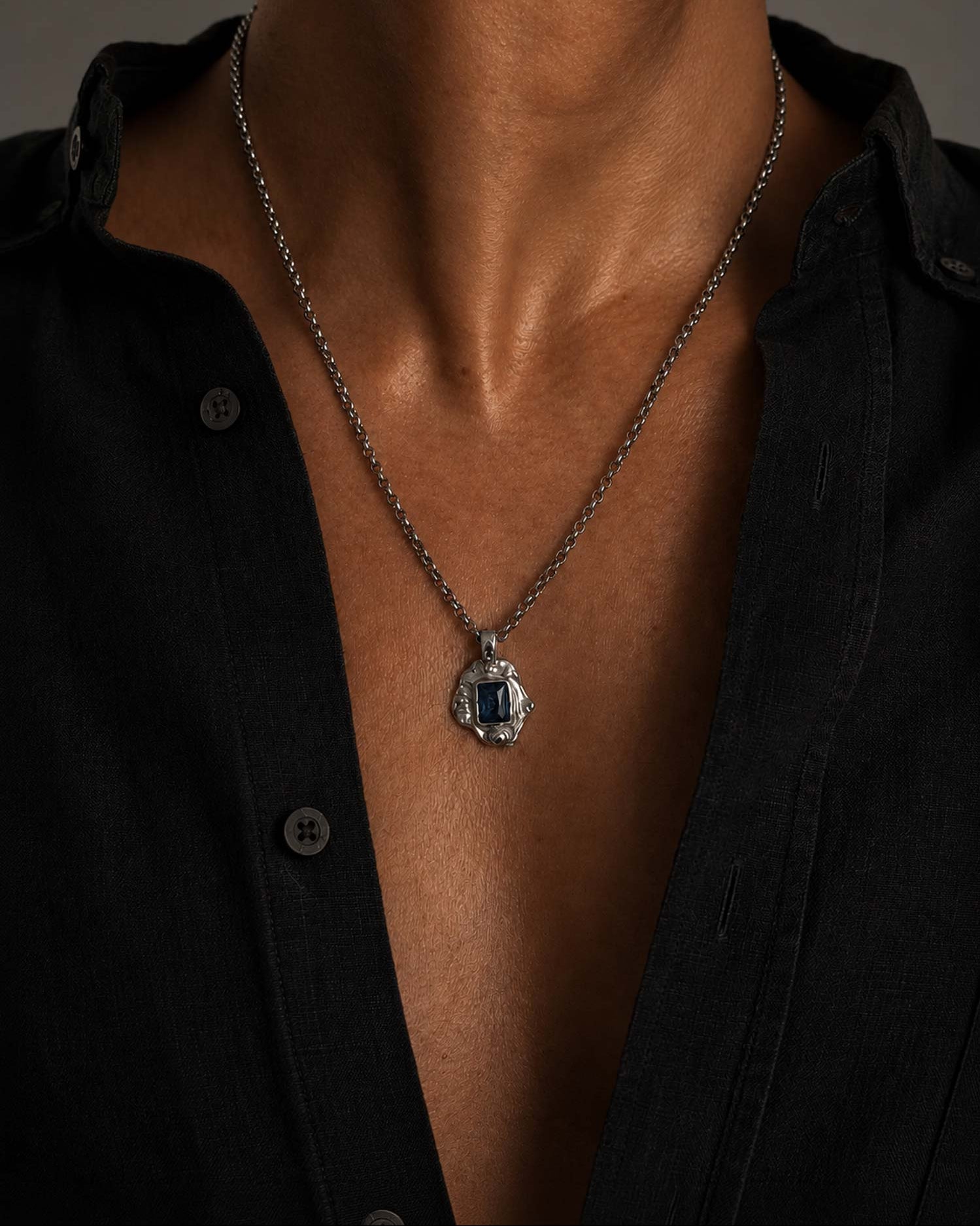 man wearing necklace with blue stone