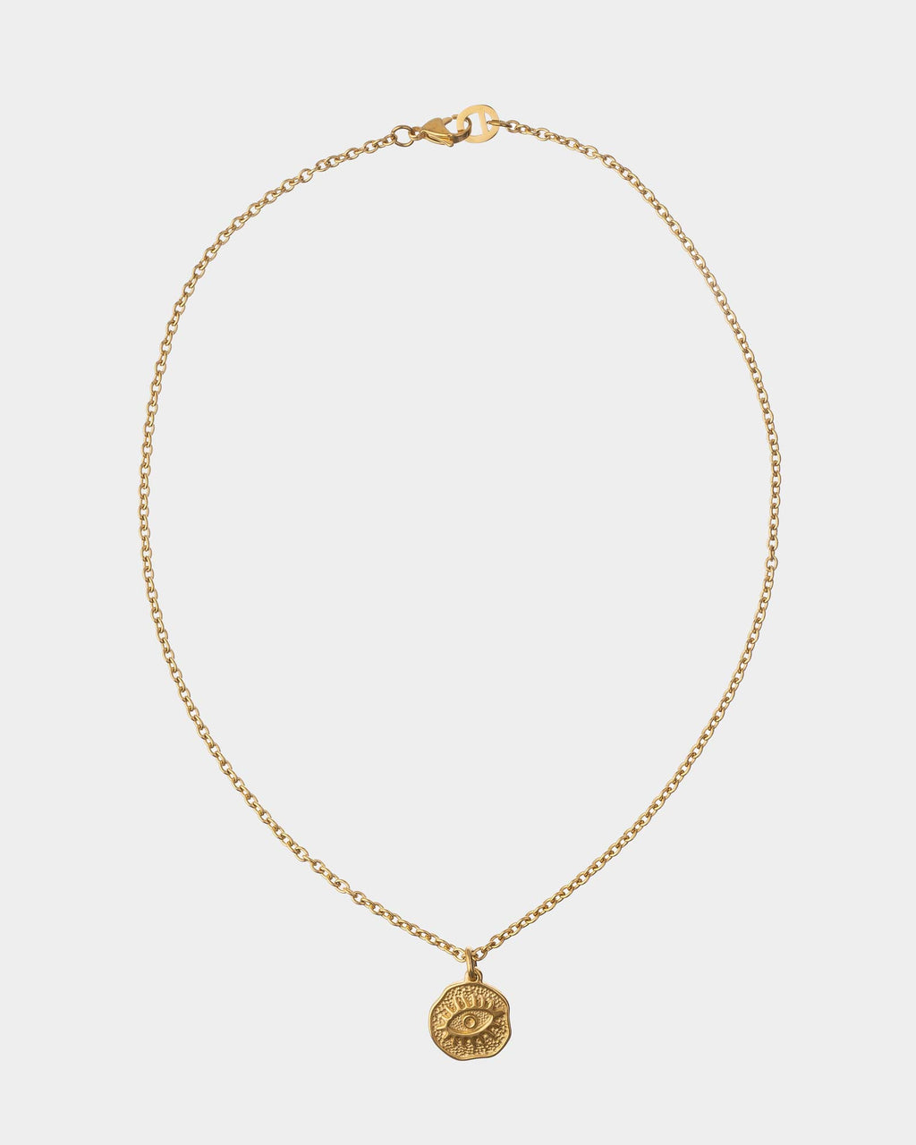 Gold necklace with a round pendant on a light gray background
