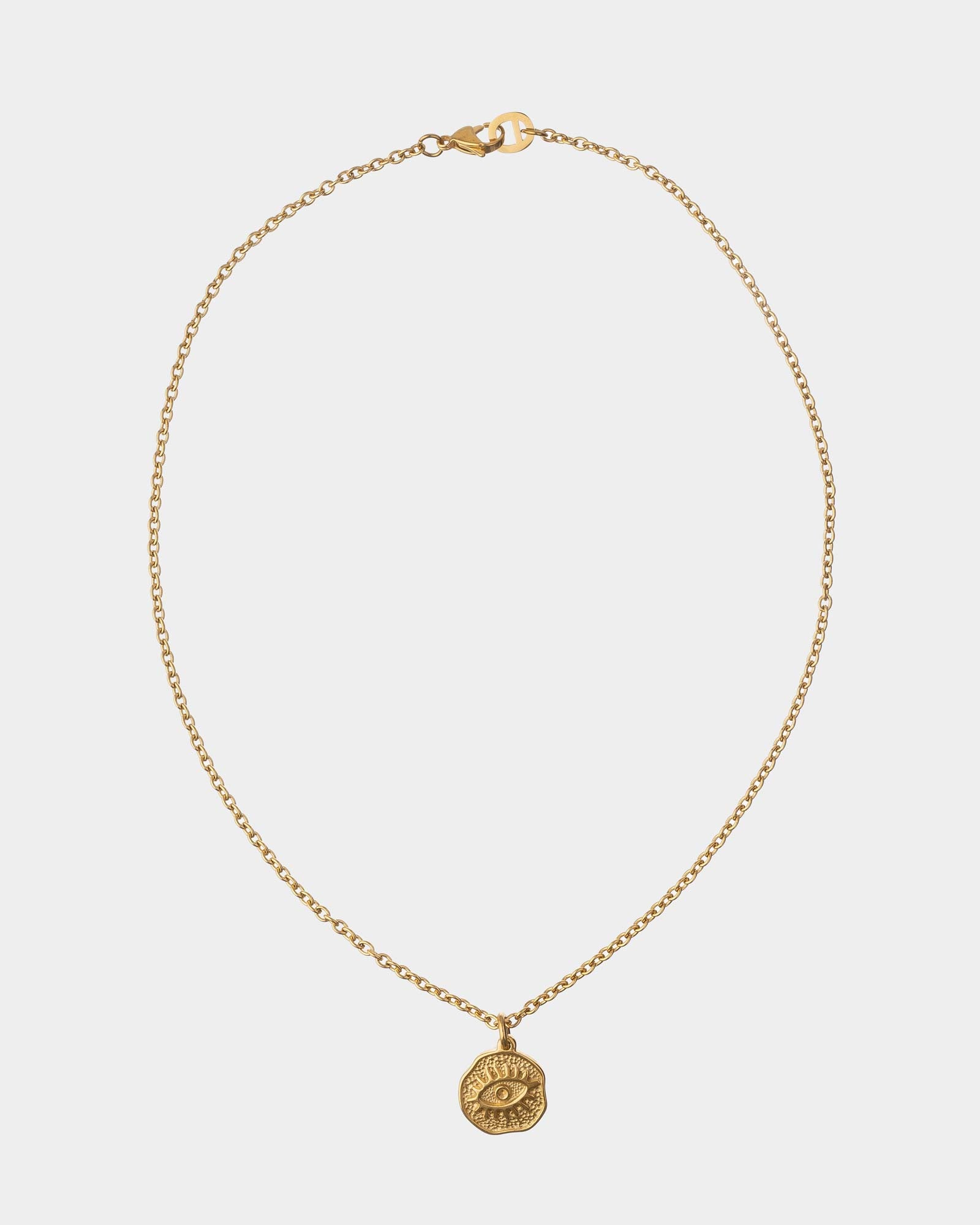 Gold necklace with a round pendant on a light gray background