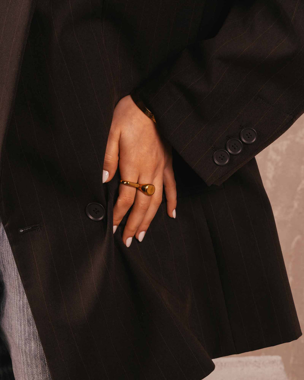 Person wearing a dark coat with a close-up of a hand and ring.