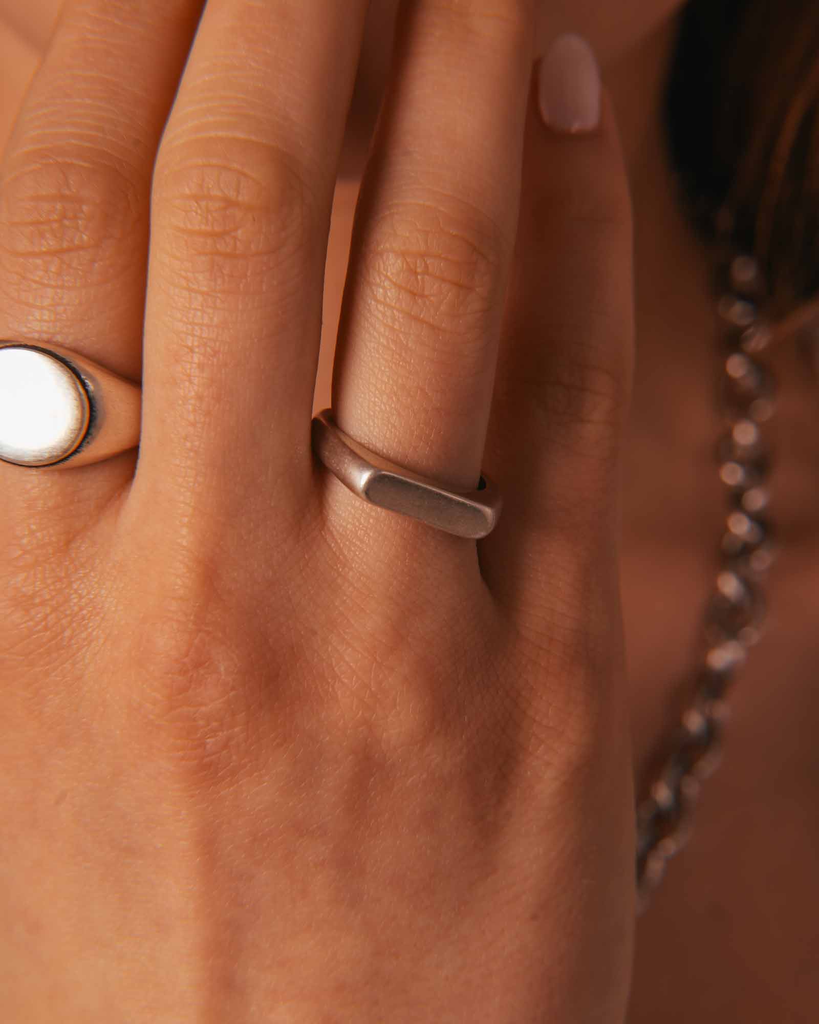 Close-up of a hand wearing two rings with a blurred background