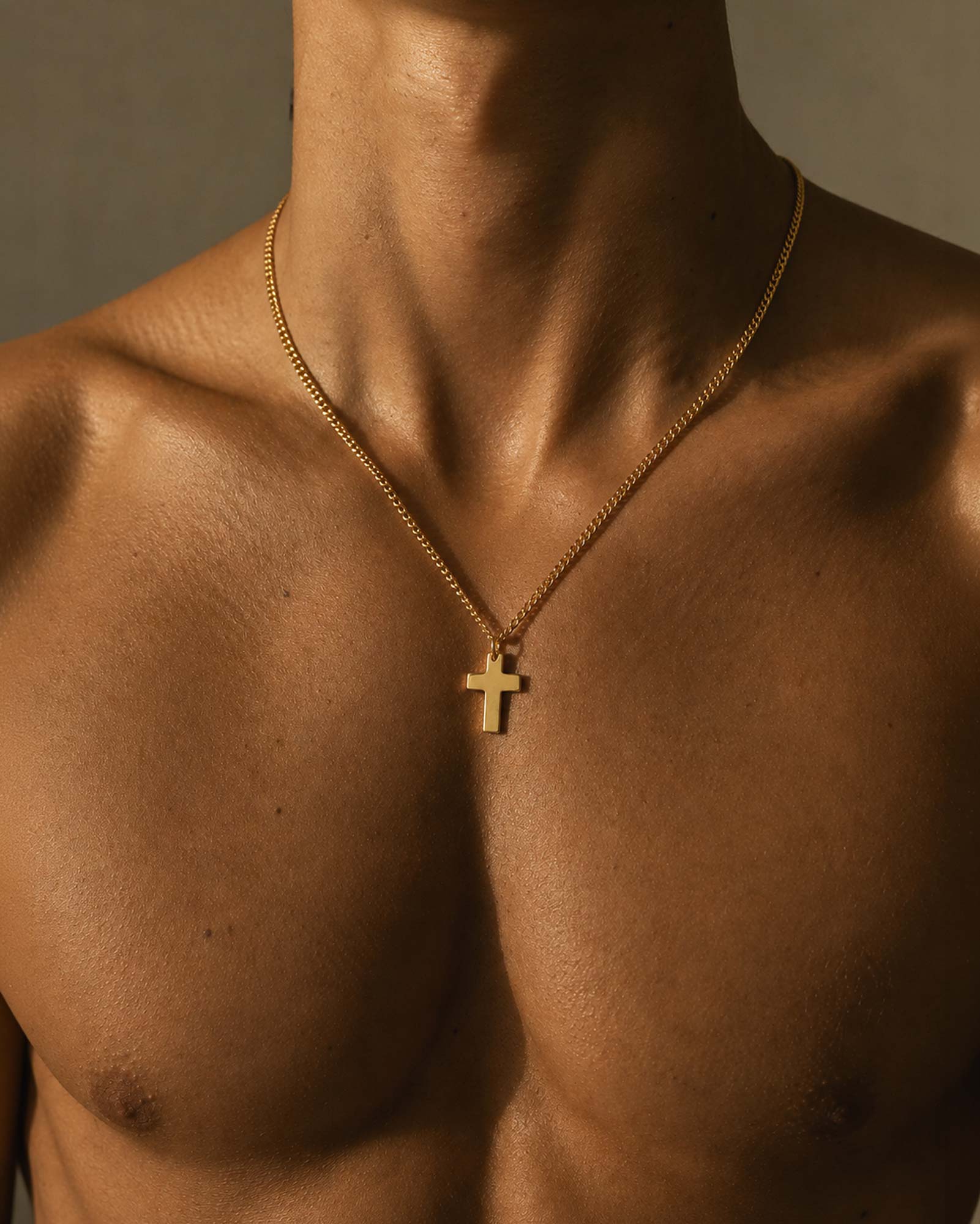 Close-up of a gold cross pendant on a neutral background