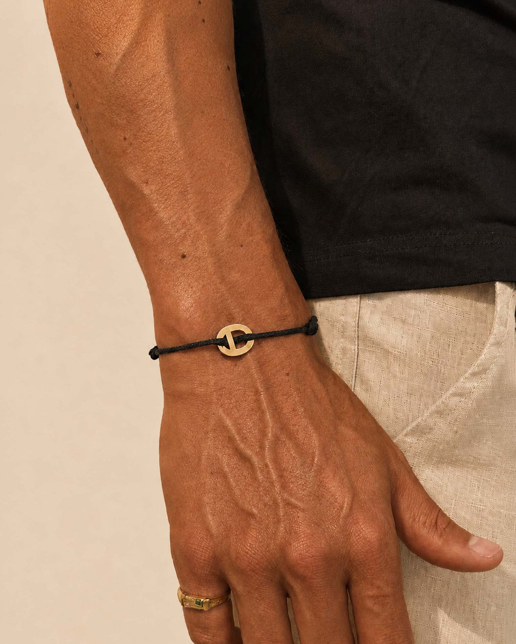 Dorato - Mano che indossa un braccialetto nero con chiusura dorata su uno sfondo neutro
