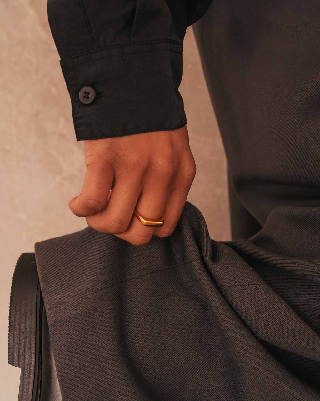 Hand holding a folded suit jacket with a blurred background