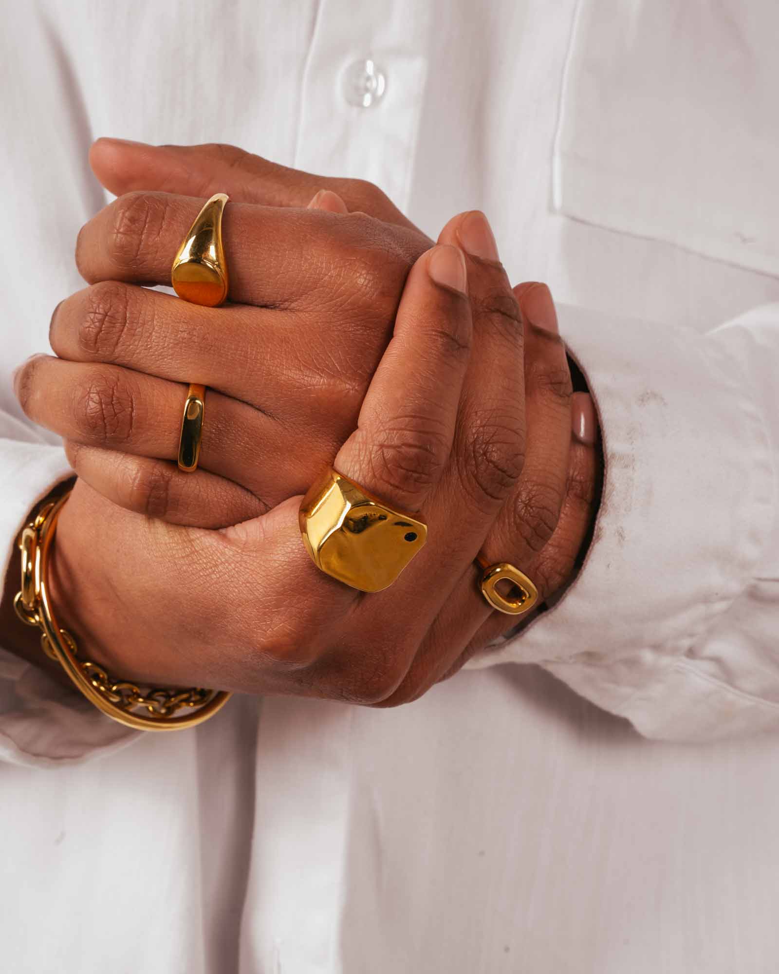 Close-up of hands wearing gold rings and bracelets on a white background