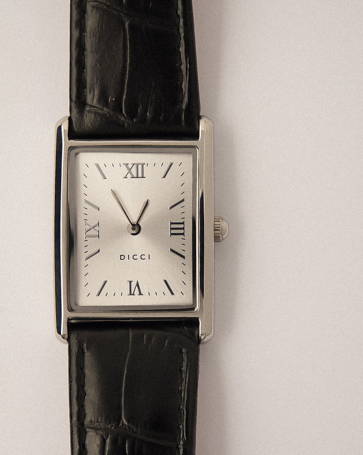 Wristwatch with black strap and silver case on a silver background