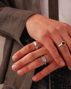 A close-up of a hand wearing a polished silver ring.