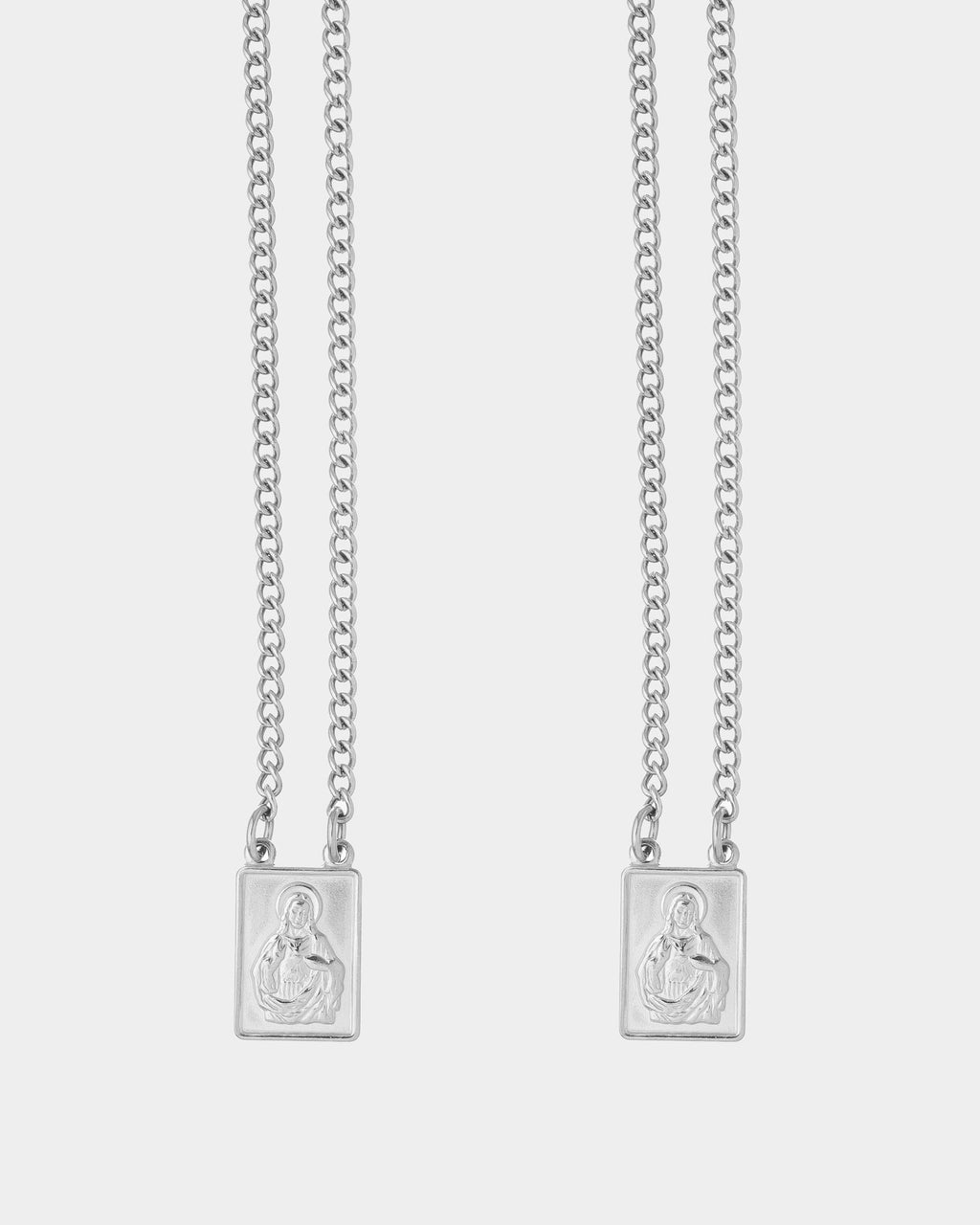 Silver - Two silver chain necklaces with rectangular pendants featuring an embossed figure, displayed against a light gray background.